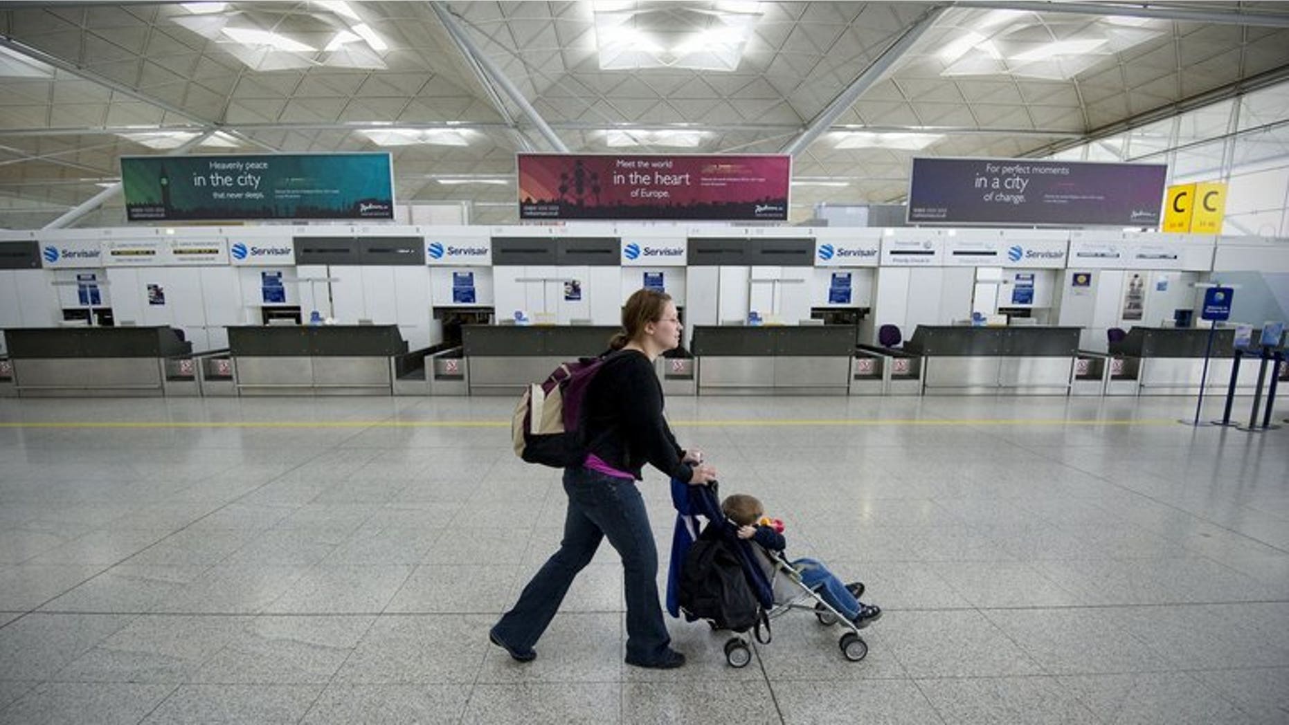 A woman pushes a buggy pasty empty check-in desks at Stansted Airport in Essex, eastern England on April 16, 2010.