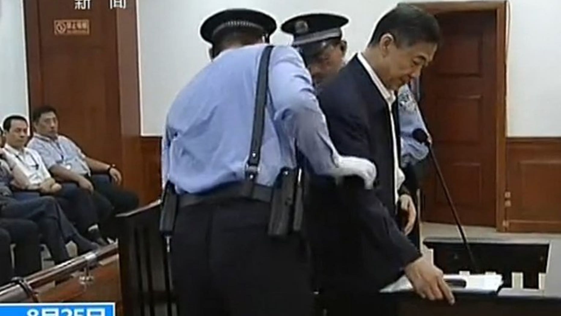 This screen grab taken from state television CCTV footage broadcast on August 25, 2013 shows ousted Chinese political star Bo Xilai (R) being helped to sit in his dock in the courtroom as he stands trial at the Intermediate People's Court in Jinan, in eastern China's Shandong province.