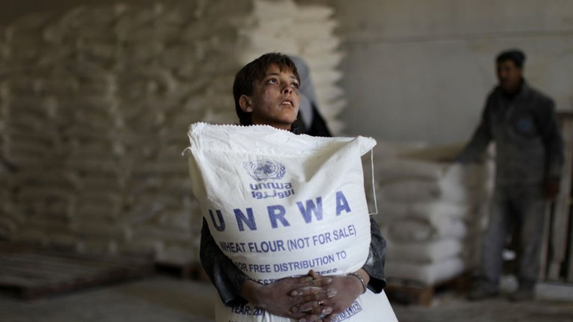 A Palestinian boy holds a sack of flour at a United Nations Relief and Works Agency (UNRWA) aid distribution centre in Gaza City, on April 10, 2013. Israel has answered EU anger over the confiscation of humanitarian aid for Palestinians with accusations diplomats at the scene defied a court order and one struck a policeman.