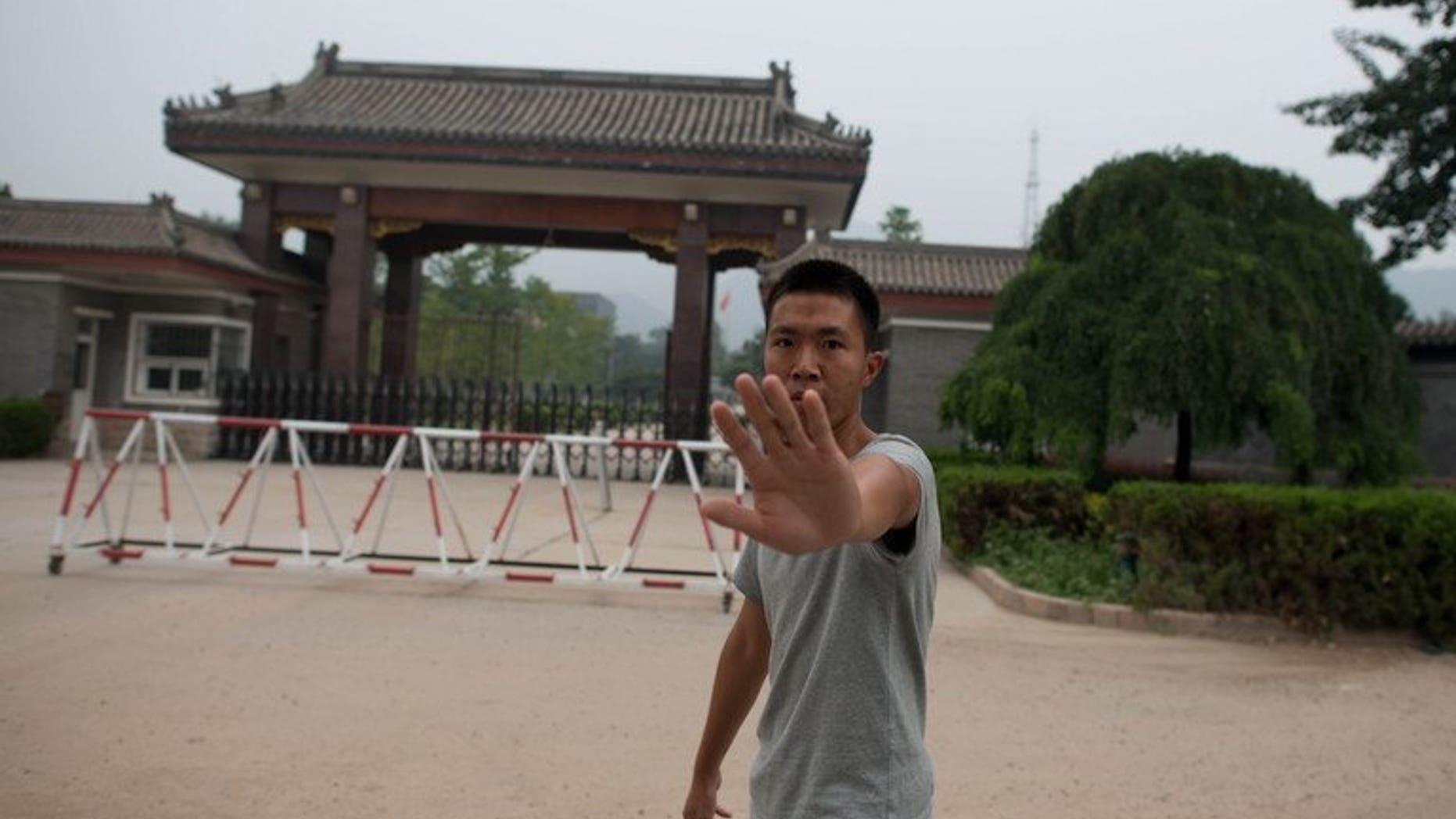 A Chinese policeman attempts to stop photos from being taken at the entrance to Qincheng prison near Beijing, on September 12, 2013. Fallen high-flyer Bo Xilai can expect hotel-style treatment at the jail for China's political elite, where he will enjoy comfortable surroundings but be constantly monitored by government agents, former prisoners have told AFP.