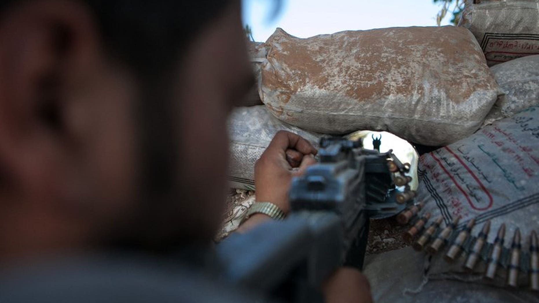 A Syrian rebel fighter points his rifle through a hole in sandbags on June 14, 2013 in Idlib.