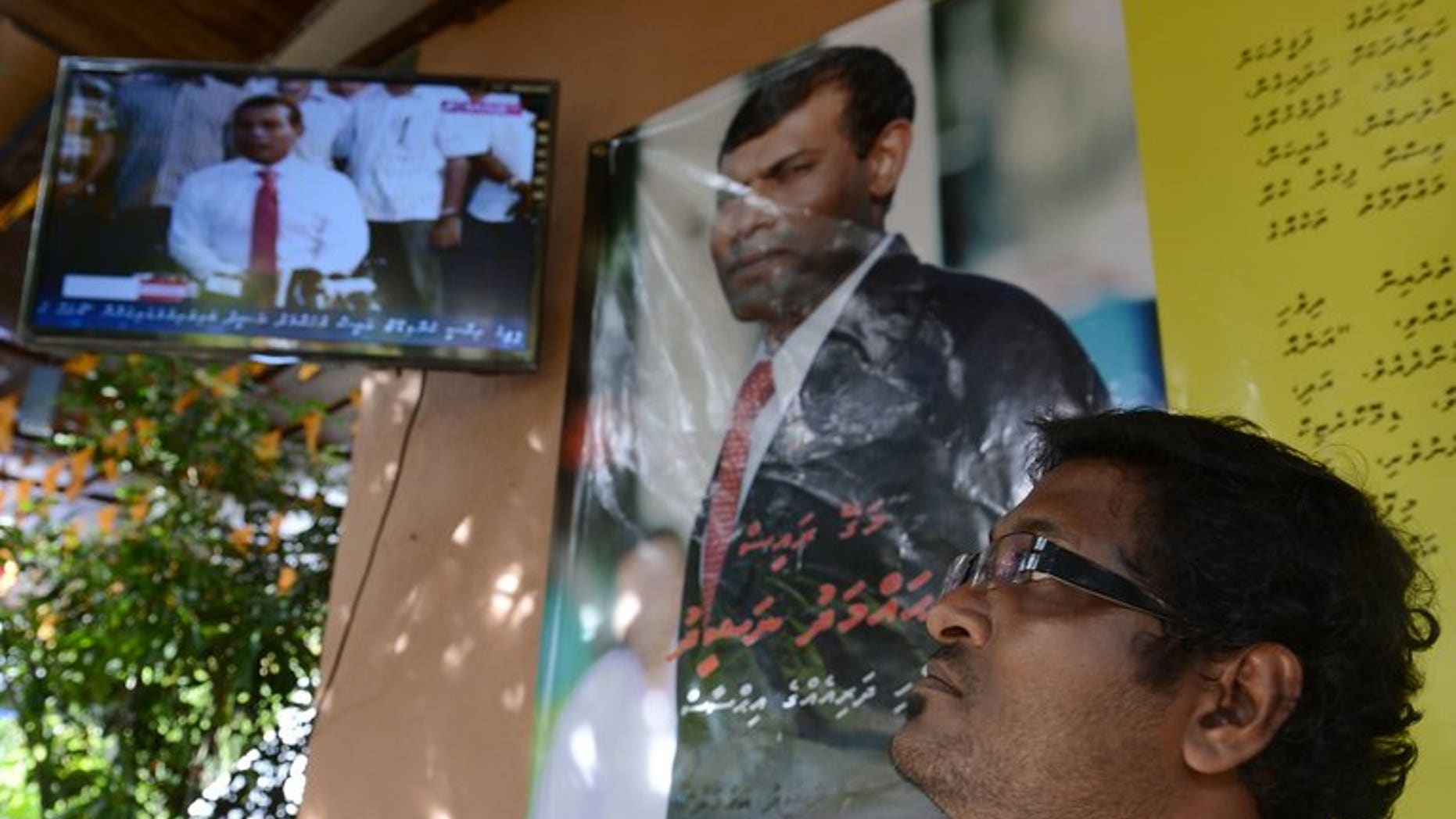A Maldivian national watches a televised live press conference in Sri Lanka's capital Colombo on September 8, 2013.