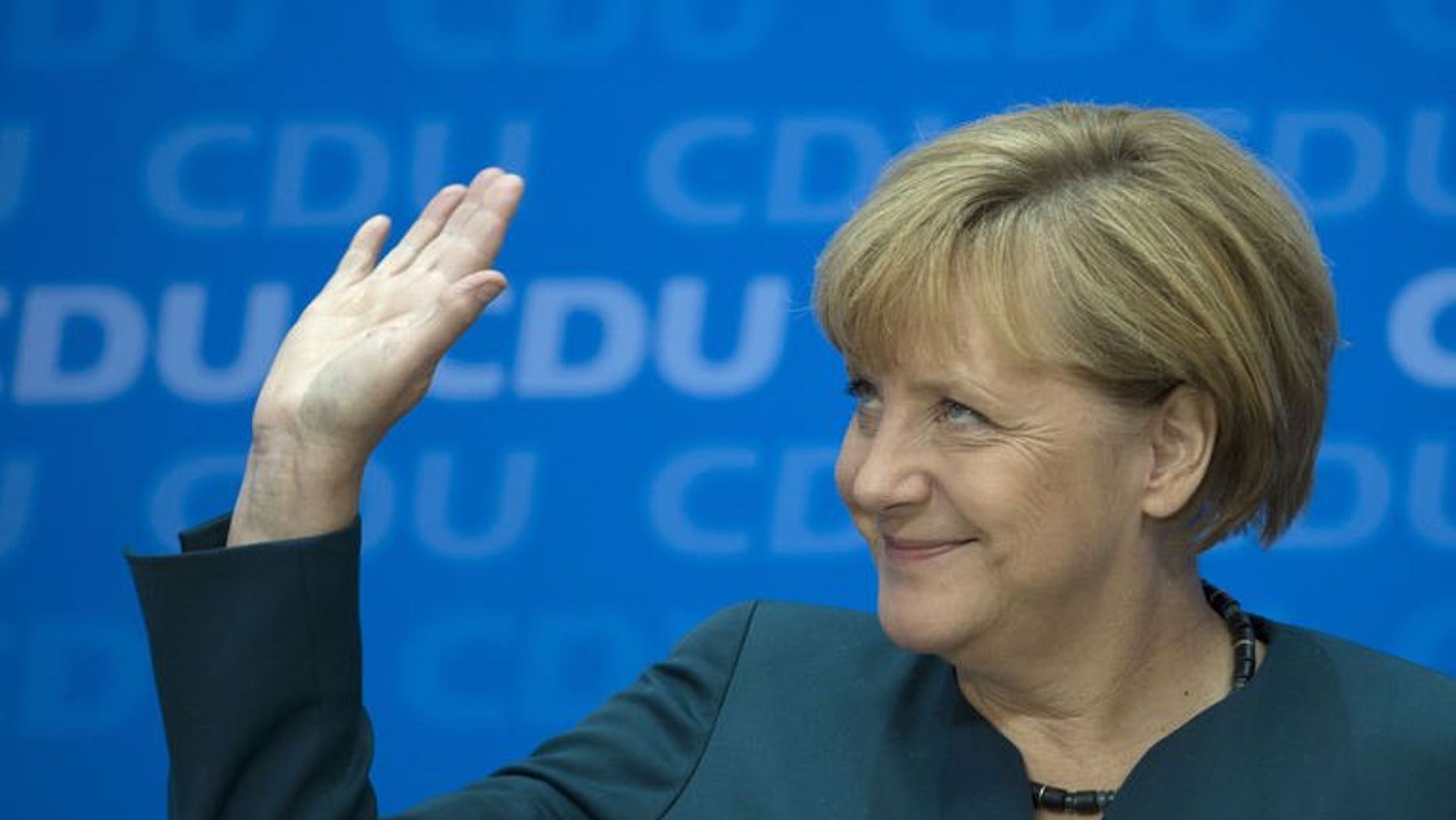 German Chancellor Angela Merkel waves as she gives a press conference in Berlin, on September 23, 2013, a day after the German general elections.