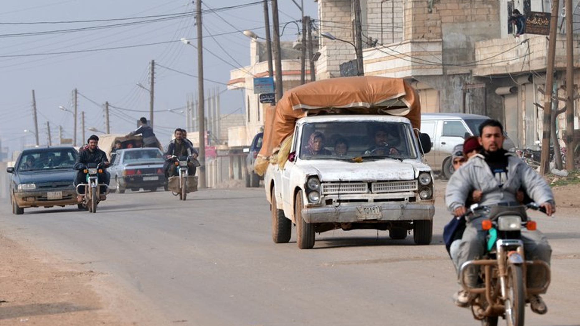 Residents drive motorcycles and cars to flee during fighting between rebels and regime forces close to Hama, on January 27, 2013.
