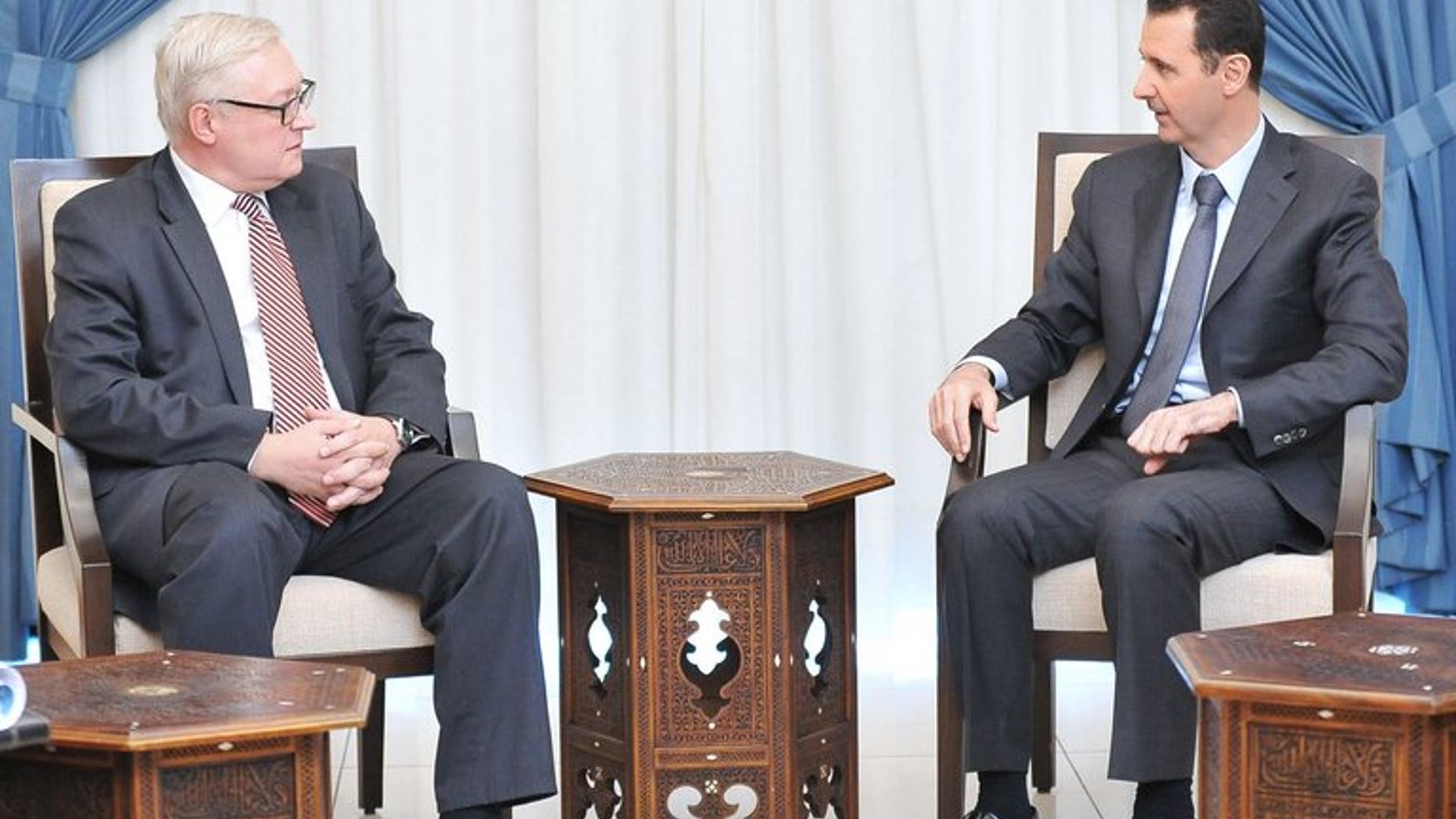 A Syrian Arab News Agency (SANA) handout from September 18, 2013 shows Russian Deputy Foreign Minister Sergei Ryabkov (left) and Syrian President Bashar al-Assad, Damascus. A UN Security Council resolution on Syria could mention Chapter VII of the UN Charter which allows force or tough sanctions, a top Russian diplomat said Tuesday.