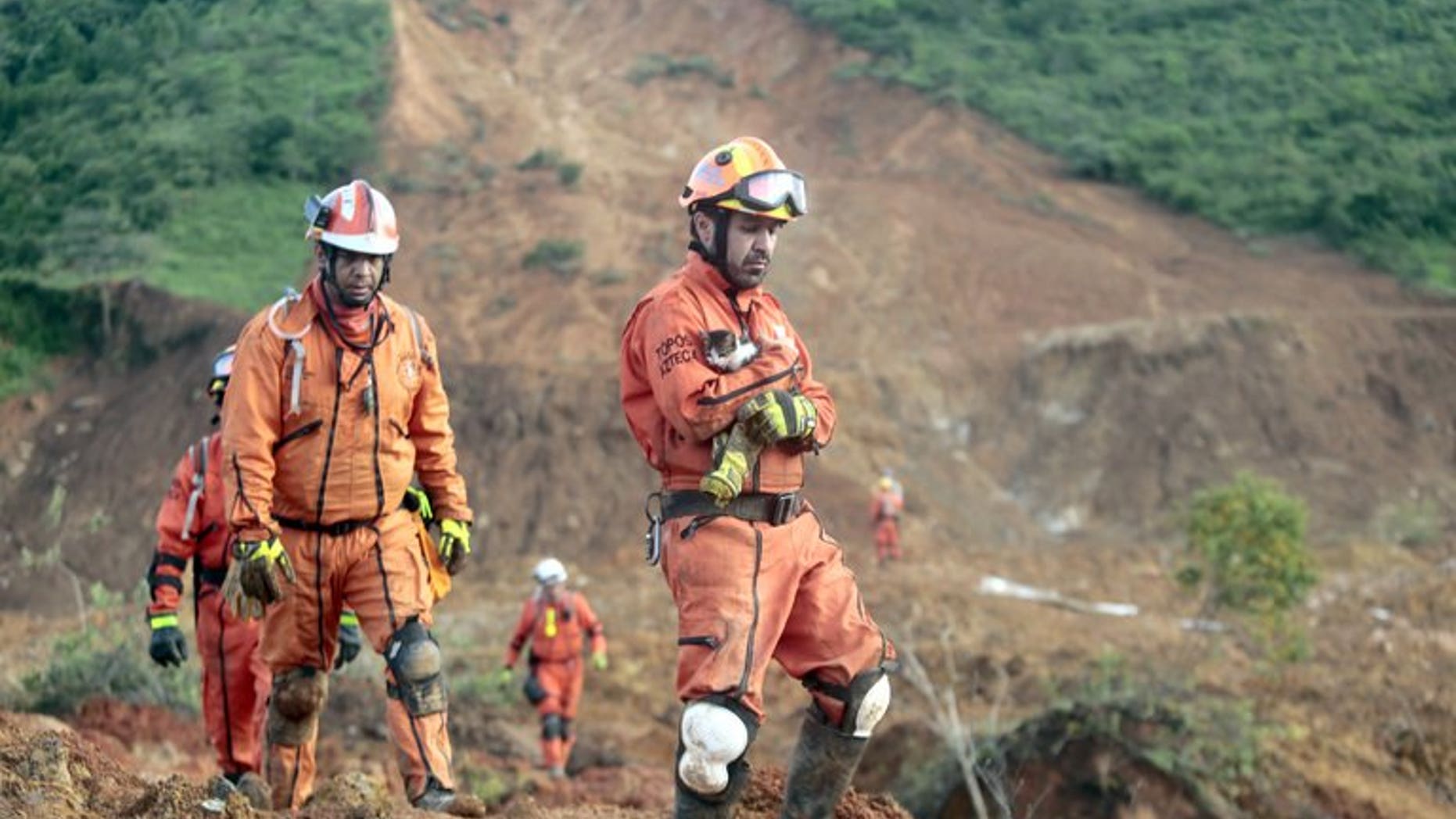 A member of the Mexican rescue team holds a kitten as others search for victims of a landslide in La Pintada, Guerrero state, on September 23, 2013. Human nature is sharing the blame with Mother Nature in Mexico for the destruction spawned by twin storms, with critics pointing to shoddy construction, endemic corruption and political wheeling-and-dealing.