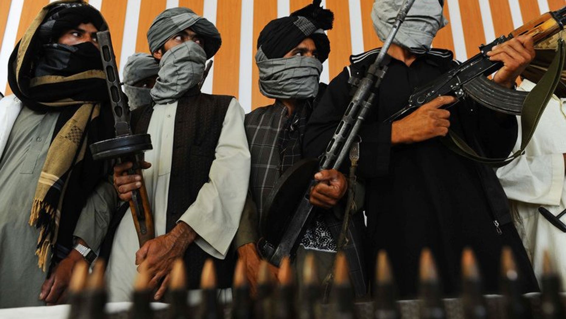 Taliban fighters stand with their weapons during a ceremony in Herat, western Afghanistan, on August 7, 2013. Mortar shells fired from Afghanistan have hit a border village in northwest Pakistan, killing two civilians, security officials told AFP.