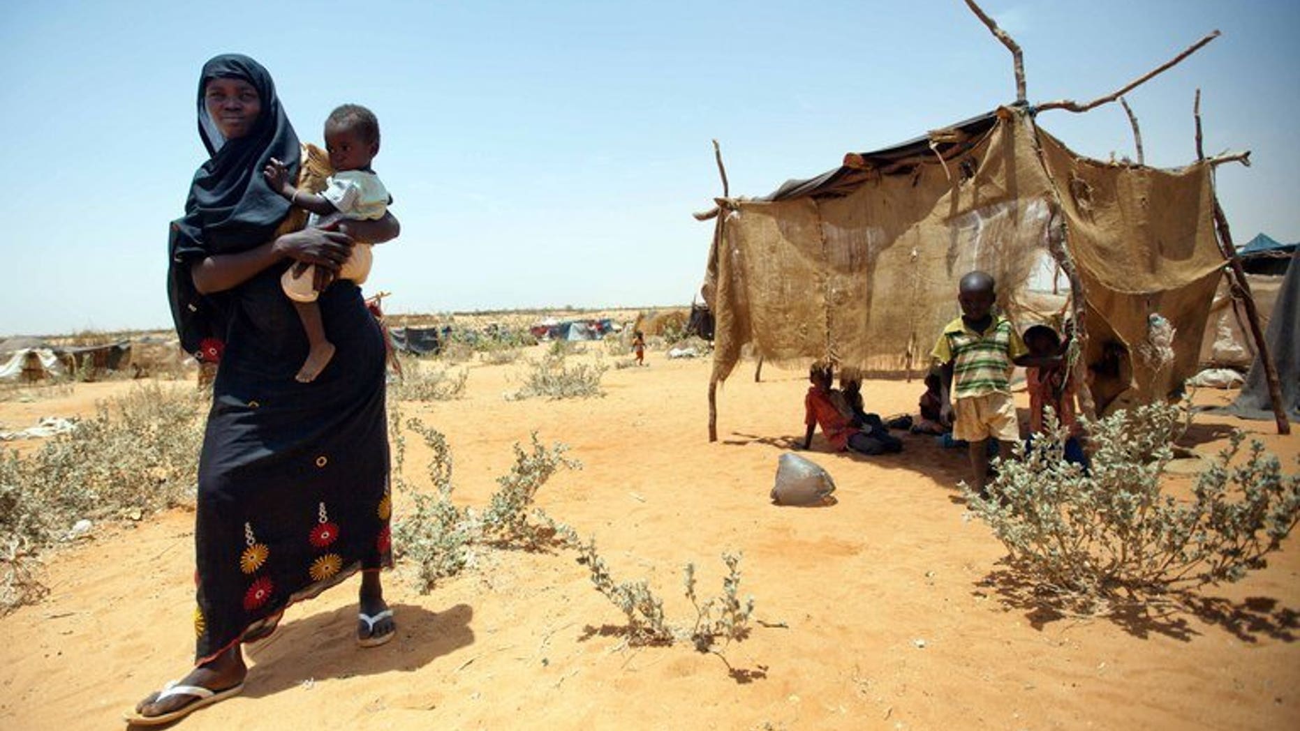 A handout from the United Nations-African Union Mission in Darfur on May 22, 2013 shows a Sudanese woman walking with her baby at the new settlement of the Zam Zam camp for Internally Displaced Persons (IDP), in North Darfur. Demonstrators protesting fuel price hikes torched the headquarters of Sudan's ruling National Congress Party in Khartoum's twin city Omdurman on Tuesday, witnesses said.