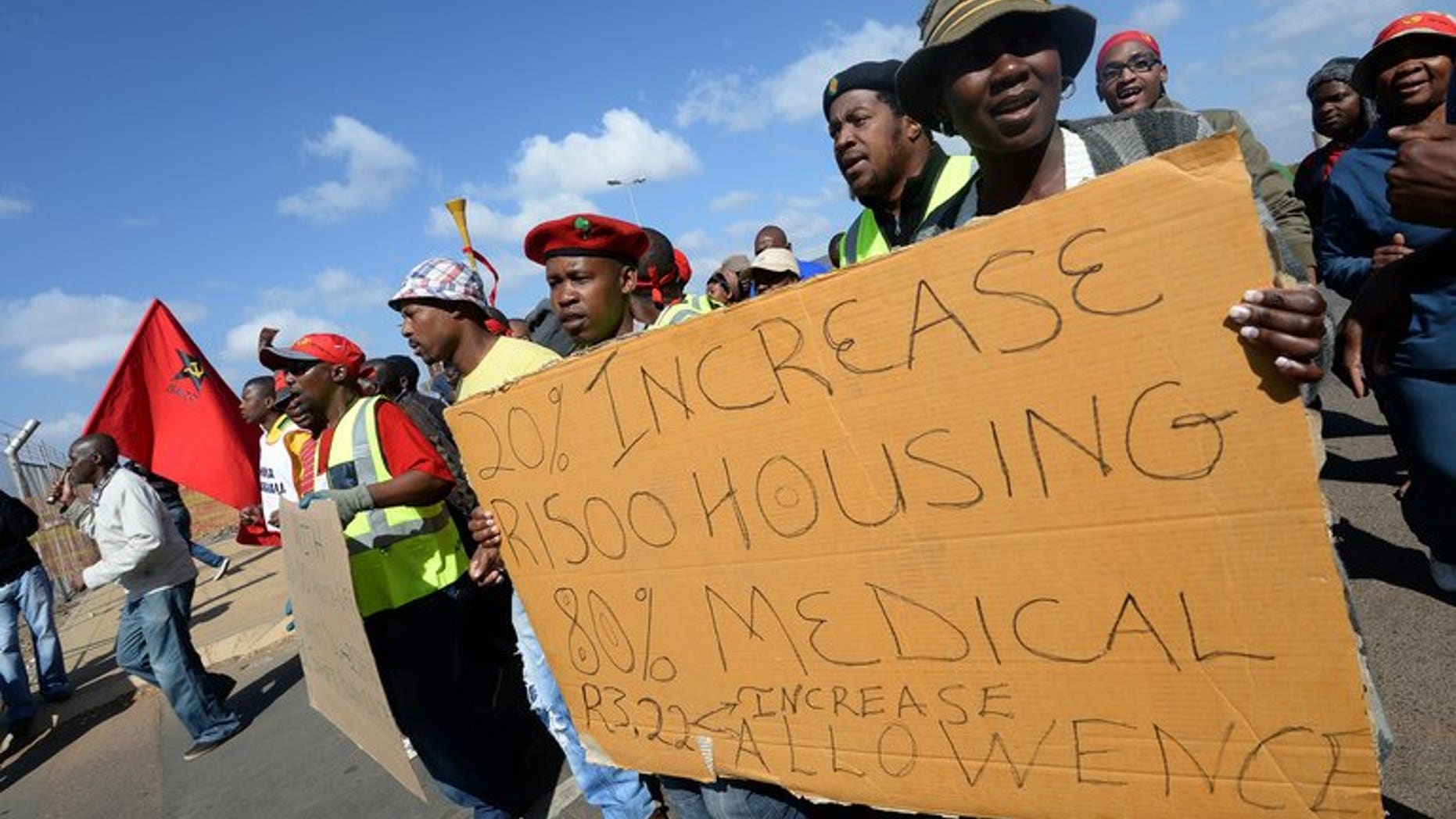 Workers on strike hold a placard asking for wage increases as they demonstrate outside Ford's plant in Pretoria on August 20, 2013.