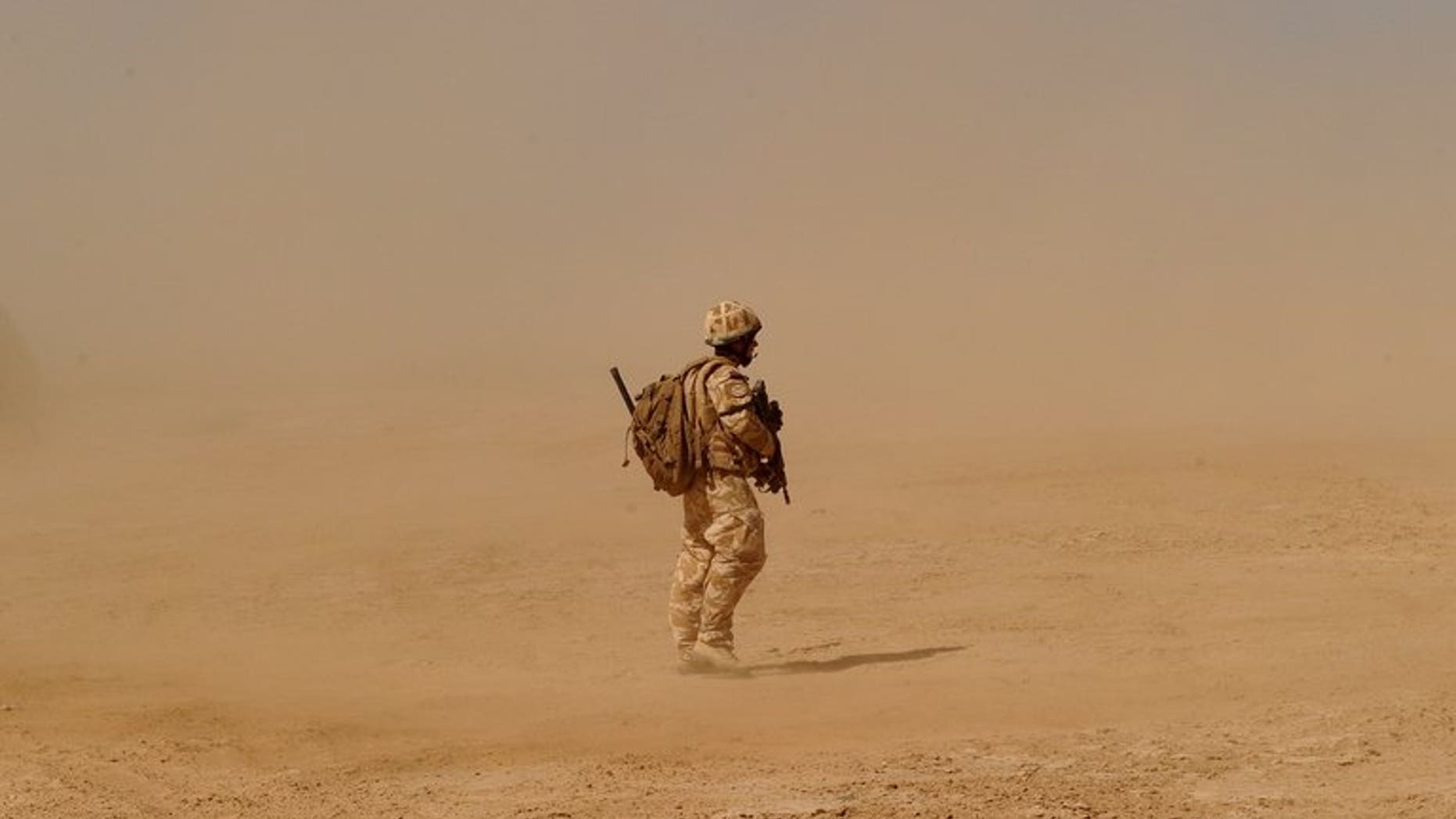 A British soldier walks near the Pimon military camp in Nad-e Ali district of Helmand province on March 25, 2010.