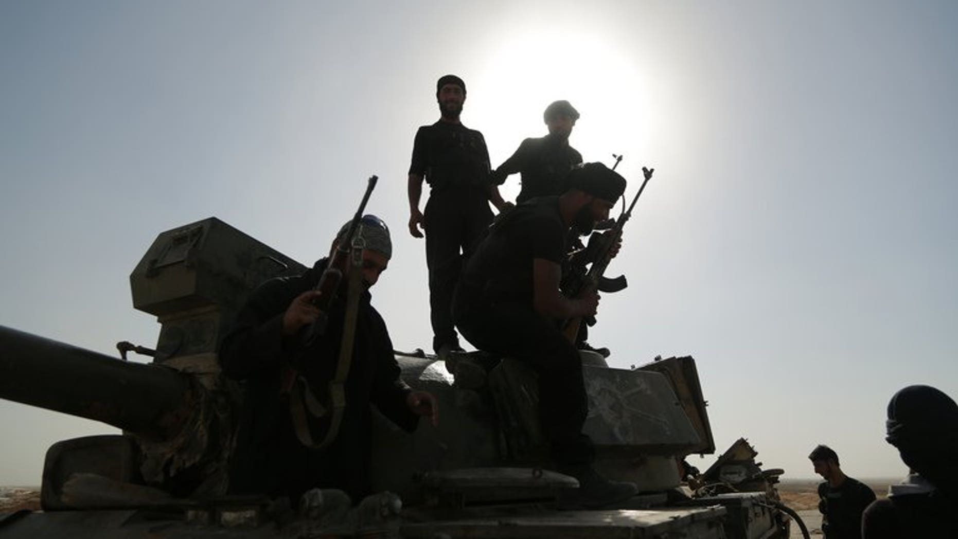 Syrian rebels inspect a tank that was left behind by government forces following clashes in the outskirts of the northern city of Raqqa on July 1, 2013.