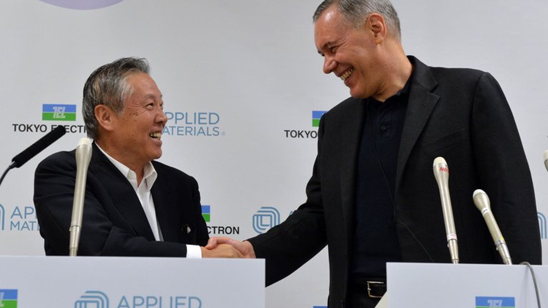 Tokyo Electron chairman Tetsuro Higashi (L) shakes hands with US semiconductor giant Applied Materials CEO Gary Dickerson (R) after they agreed to merge, in Tokyo on September 24, 2013.