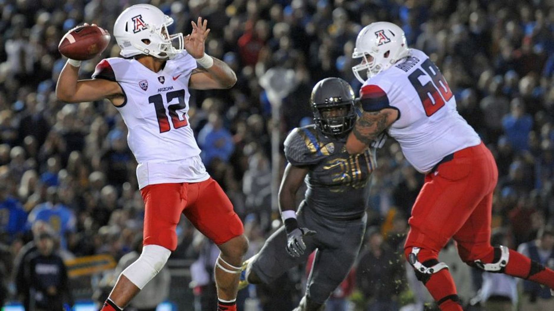 Nov 1, 2014; Pasadena, CA, USA; Arizona Wildcats quarterback Anu Solomon (12) passes the ball as offensive lineman Mickey Baucus (68) blocks UCLA Bruins linebacker Myles Jack (30) during the first quarter at Rose Bowl. Mandatory Credit: Jake Roth-USA TODAY Sports
