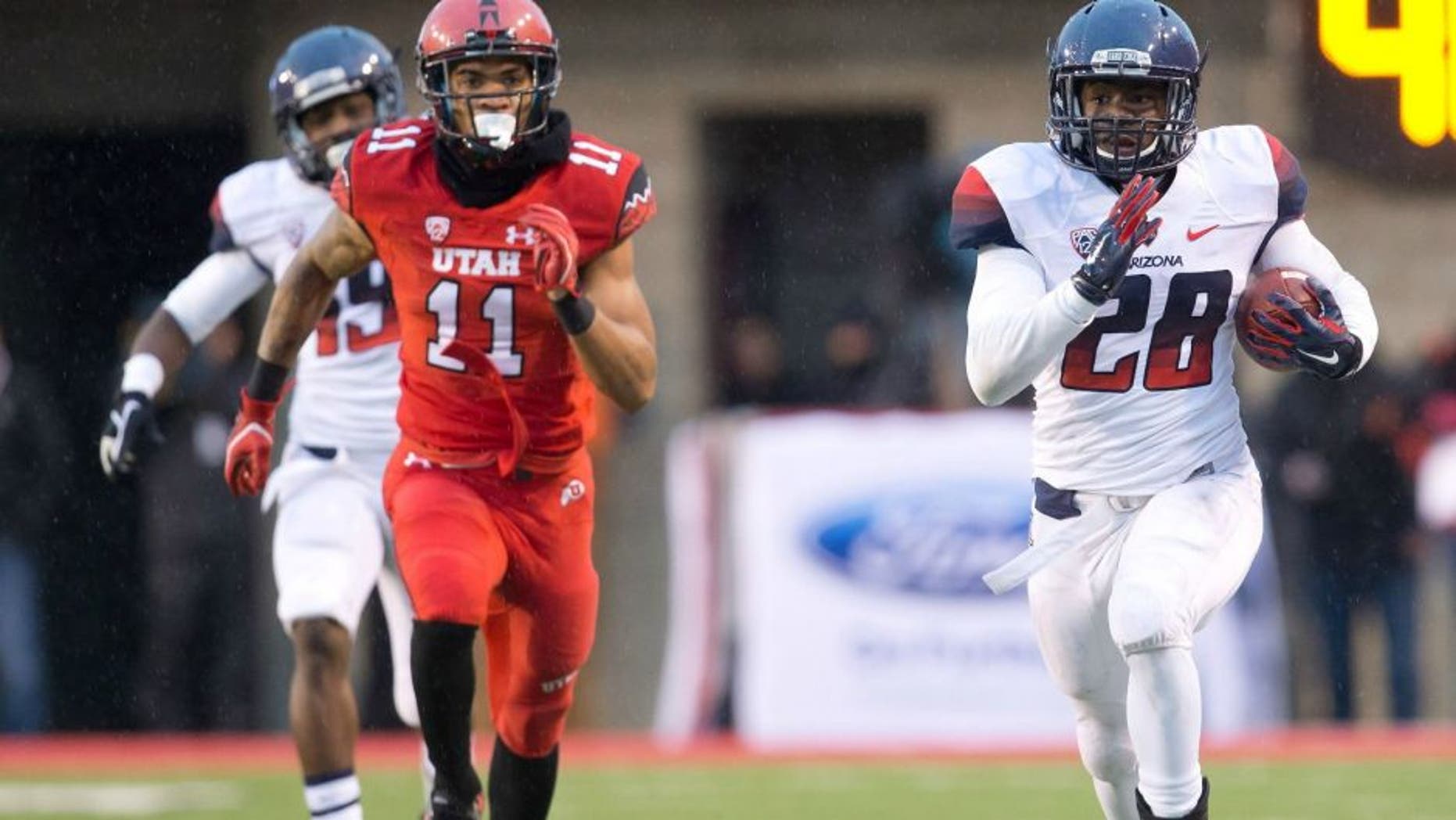 Nov 22, 2014; Salt Lake City, UT, USA; Arizona Wildcats running back Nick Wilson (28) runs with the ball up the sideline while pursued by Utah Utes defensive back Davion Orphey (11) during the first half at Rice-Eccles Stadium. Mandatory Credit: Russ Isabella-USA TODAY Sports