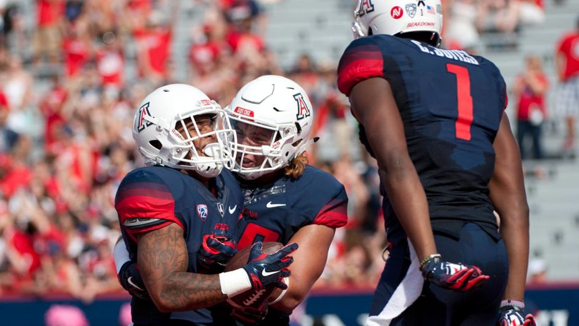 Oct 10, 2015; Tucson, AZ, USA; Arizona Wildcats running back Orlando Bradford (21) is congratulated by offensive lineman Layth Friekh (58) and wide receiver Cayleb Jones (1) after scoring a touchdown during the second quarter against the Oregon State Beavers at Arizona Stadium. Mandatory Credit: Casey Sapio-USA TODAY Sports