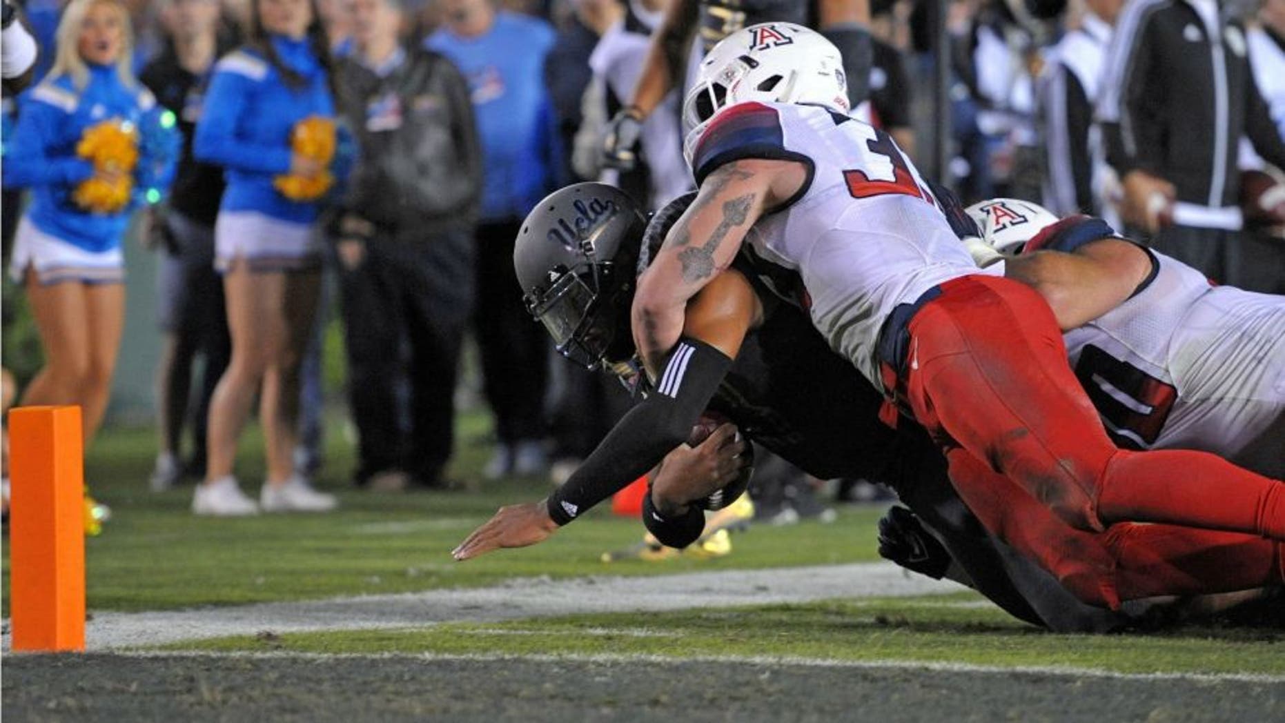 Nov 1, 2014; Pasadena, CA, USA; UCLA Bruins quarterback Brett Hundley (17) dives to the 2 yard line as Arizona Wildcats linebacker Scooby Wright III (33) brings him down during the second quarter at Rose Bowl. Mandatory Credit: Jake Roth-USA TODAY Sports