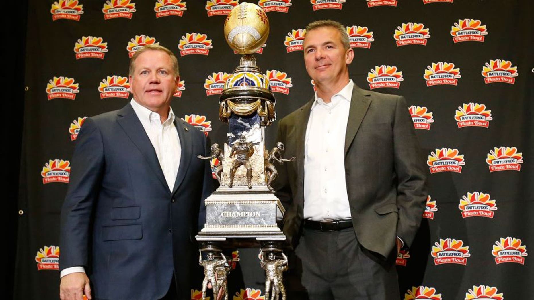 Notre Dame head coach Brian Kelly, left, and Ohio State head coach Urban Meyer pose with the trophy during a news conference for the Fiesta Bowl NCAA college football game, Thursday, Dec. 31, 2015, in Scottsdale, Ariz. Notre Dame plays Ohio State on New Year's Day. (AP Photo/Rick Scuteri)