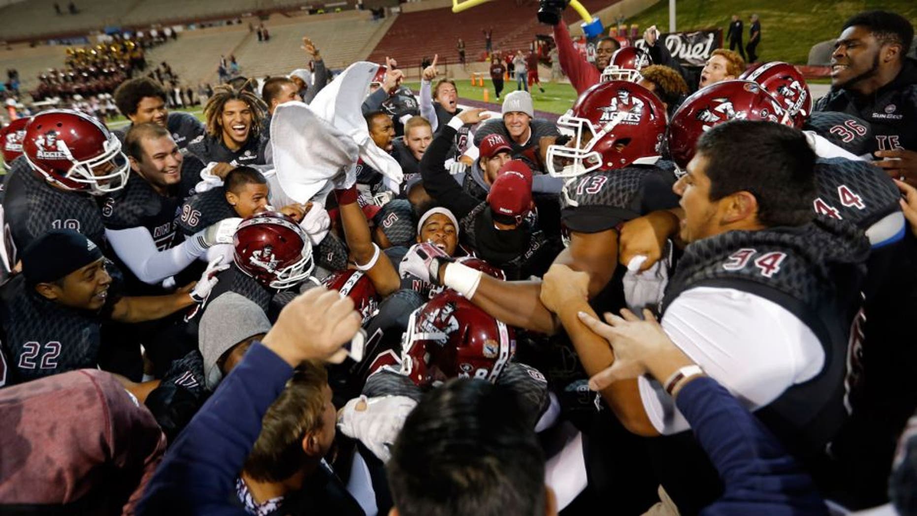 The New Mexico State team celebrate after defensive back Terrill Hanks intercepted a pass from Idaho quarterback Matt Linehan to win 55-48 in overtime their NCAA college football game in Las Cruces, N.M., Saturday, Oct. 31, 2015. (AP Photo/Andres Leighton)