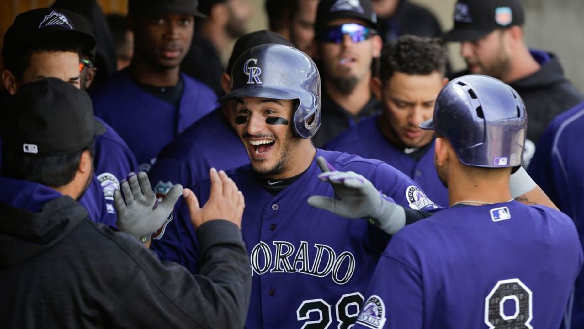 Colorado Rockies' Nolan Arenado, center, is congratulated in the dugout after hitting his second home run of the game during the fifth inning of a spring training baseball game against the Arizona Diamondbacks Tuesday, March 29, 2016, in Scottsdale, Ariz. (AP Photo/Jae C. Hong)