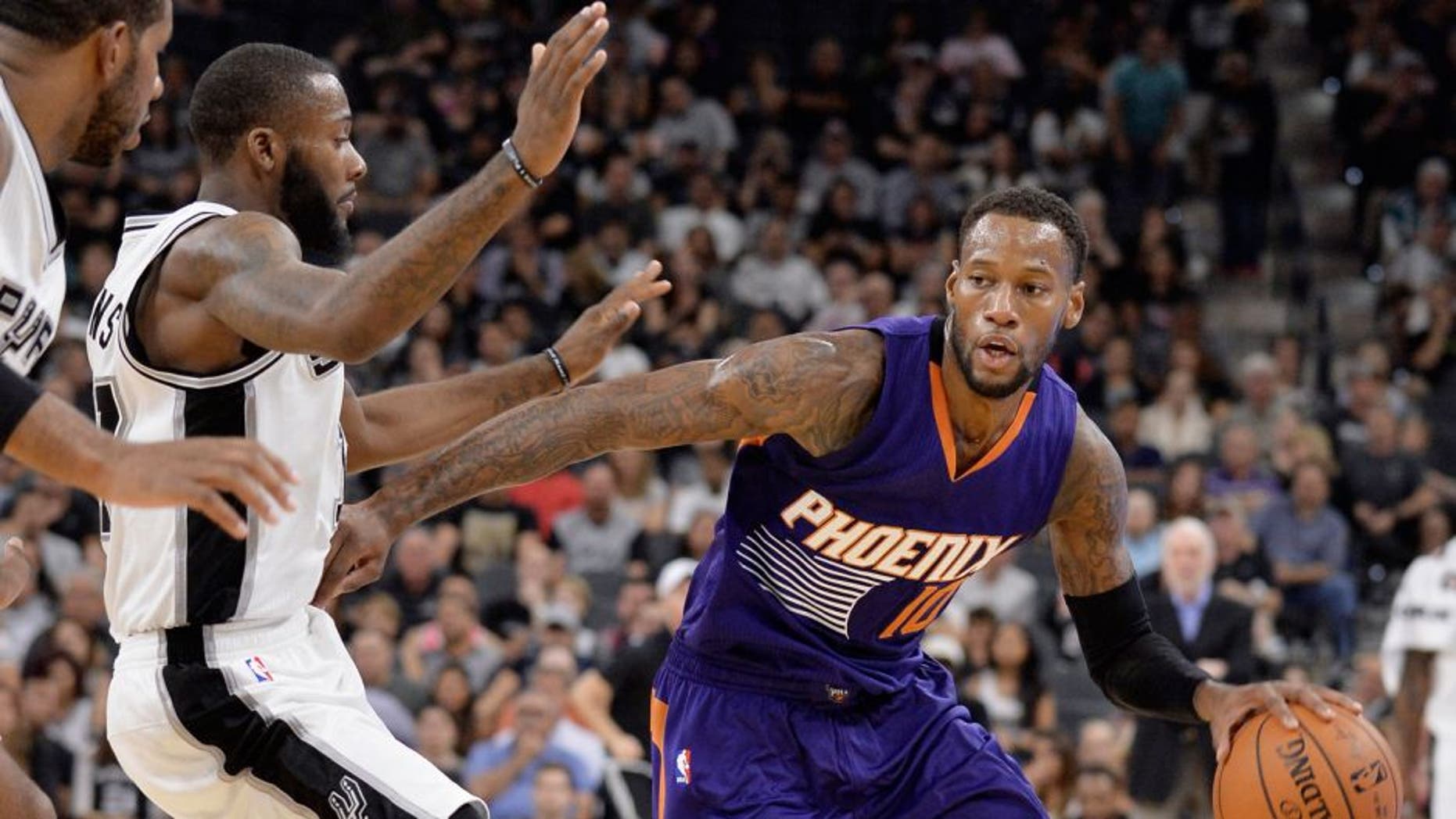 Phoenix Suns guard Sonny Weems (10) drives around San Antonio Spurs forwards Jonathon Simmons and LaMarcus Aldridge, left, during the first half of a preseason NBA basketball game, Tuesday, Oct. 20, 2015, in San Antonio. (AP Photo/Darren Abate)