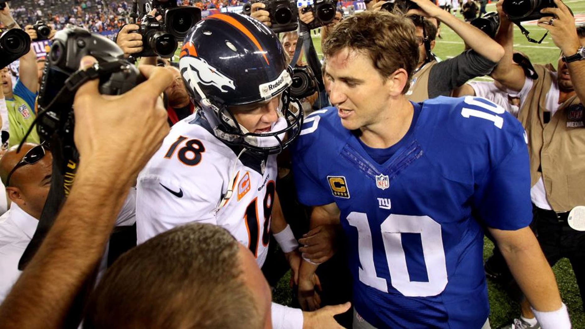 Sep 15, 2013; East Rutherford, NJ, USA; Denver Broncos quarterback Peyton Manning (18) shakes hands with New York Giants quarterback Eli Manning (10) after a game at MetLife Stadium. The Broncos defeated the Giants 41-23. Mandatory Credit: Brad Penner-USA TODAY Sports