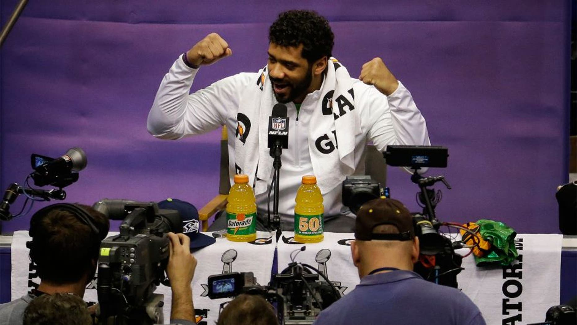 Seattle Seahawks' Russell Wilson gestures during media day for NFL Super Bowl XLIX football game Tuesday, Jan. 27, 2015, in Phoenix. (AP Photo/Charlie Riedel)