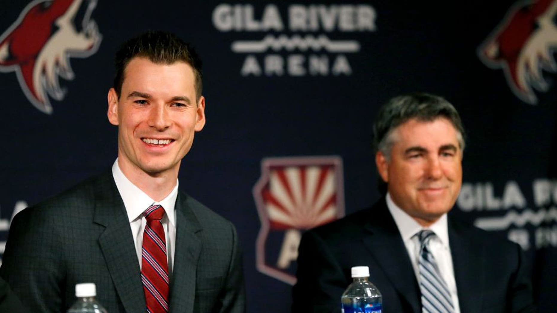 Newly appointed Arizona Coyotes general manager John Chayka speaks at a news conference announcing his promotion as head coach Dave Tippett listens, Thursday, May 5, 2016, in Glendale, Ariz. Chayka is the youngest GM in NHL history. (AP Photo/Matt York)