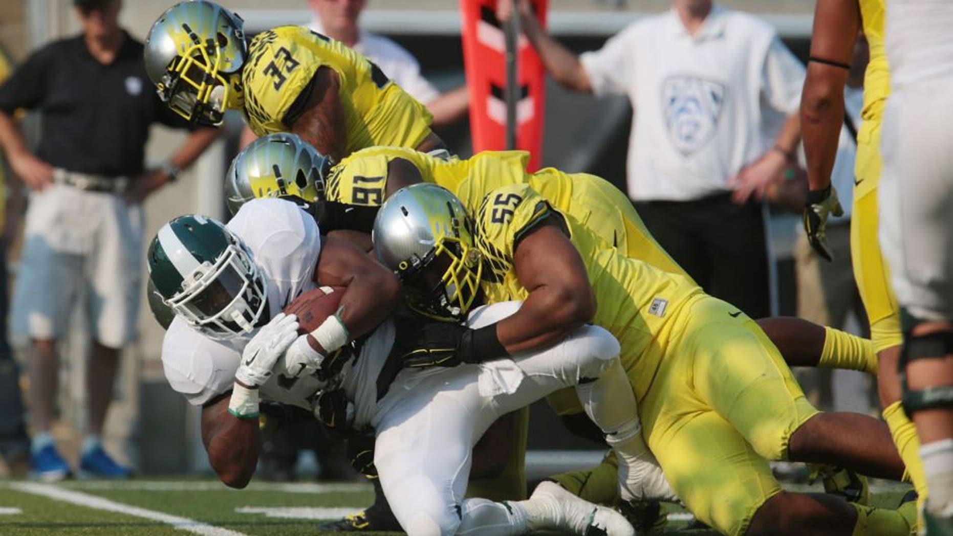 Sep 6, 2014; Eugene, OR, USA; Oregon Ducks linebacker Tony Washington (91) and defensive lineman Tui Talia (55) tackle Michigan State Spartans running back Jeremy Langford (33) at Autzen Stadium. Mandatory Credit: Scott Olmos-USA TODAY Sports