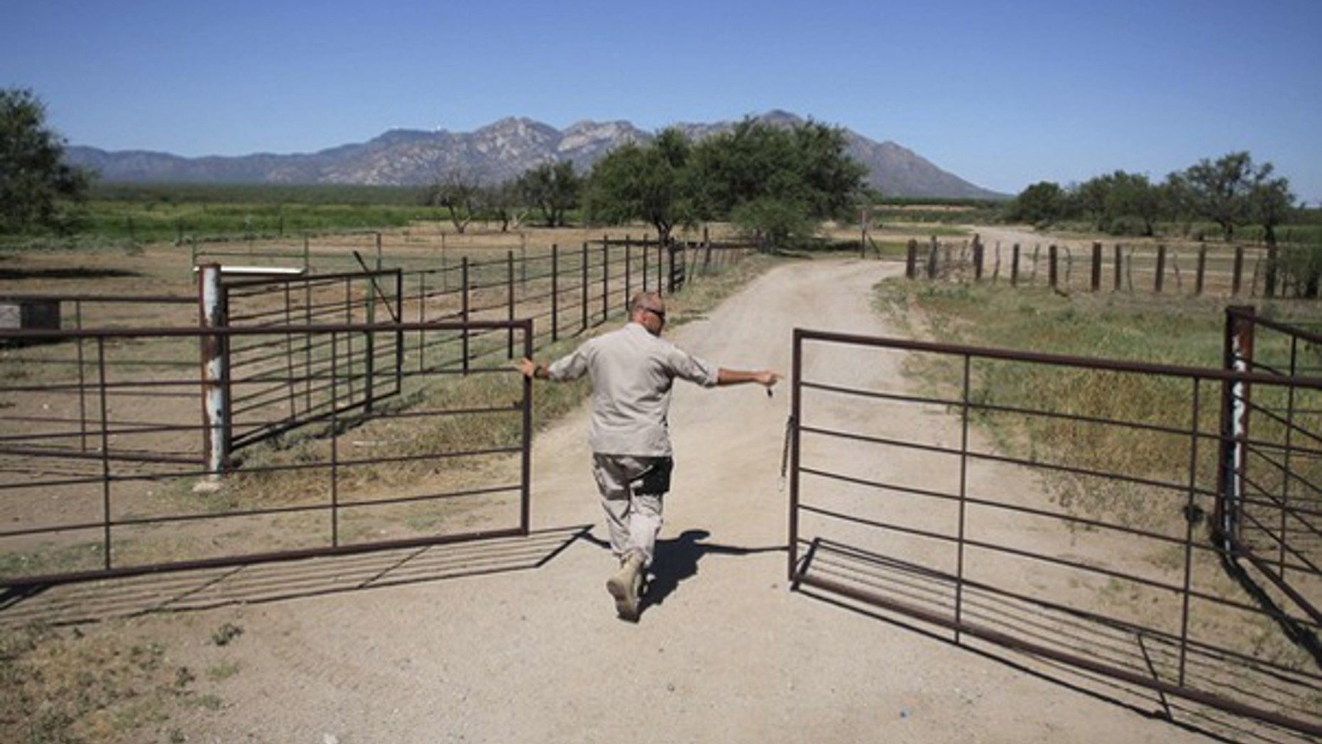 A Border Patrol agent opens a gate leading to a dirt road as he searches for illegal immigrants in the dessert of Pima County, Ariz., Aug. 17, 2009. (Reuters Photo)