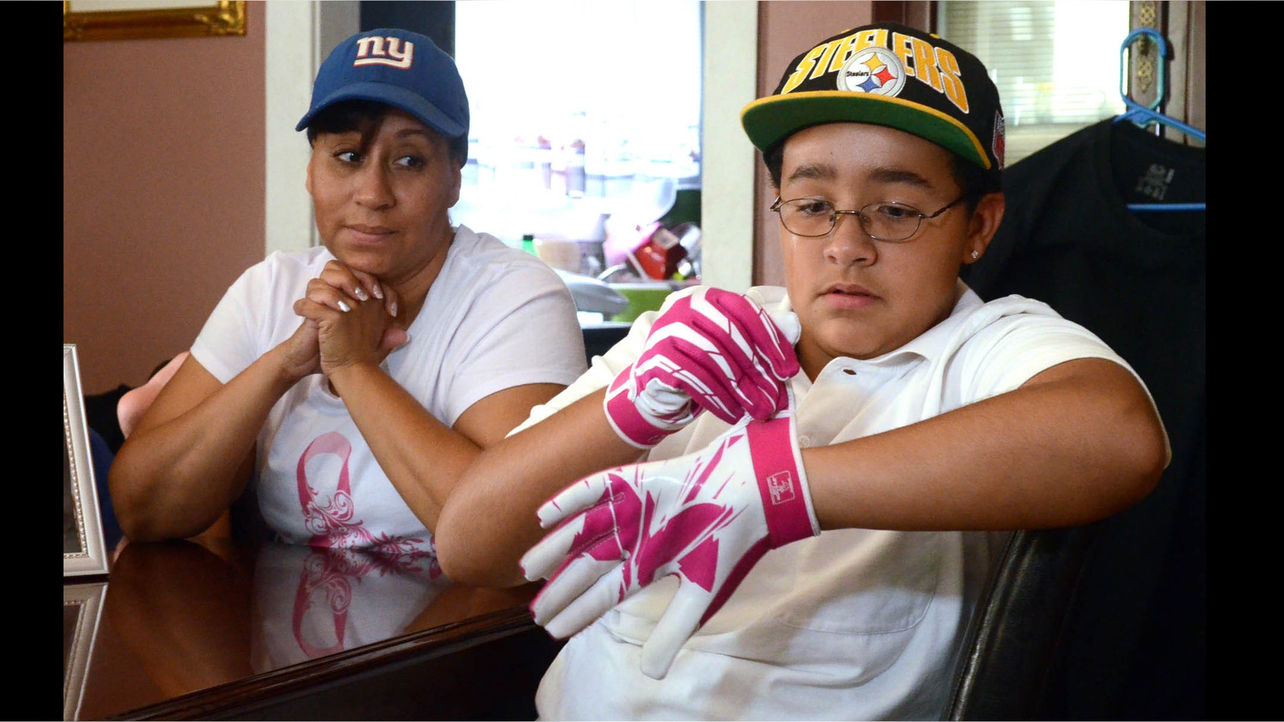Julian Connerton wears his pink football gloves that he bought in honor of his mom Mayra Cruz-Connerton, who has breast cancer, at their home in Egg Harbor City, N.J. Photo/The Press of Atlantic City, Danny Drake)