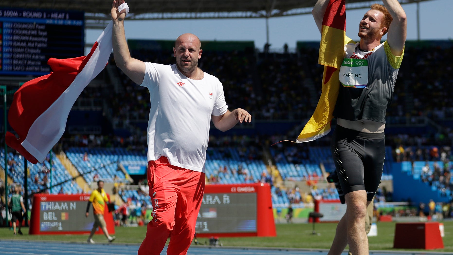 Aug. 13, 2016: Poland's silver medal winner Piotr Malachowski, left, and Germany's gold medal winner Christoph Harting celebrate with their countries flags after the men's discus throw final.
