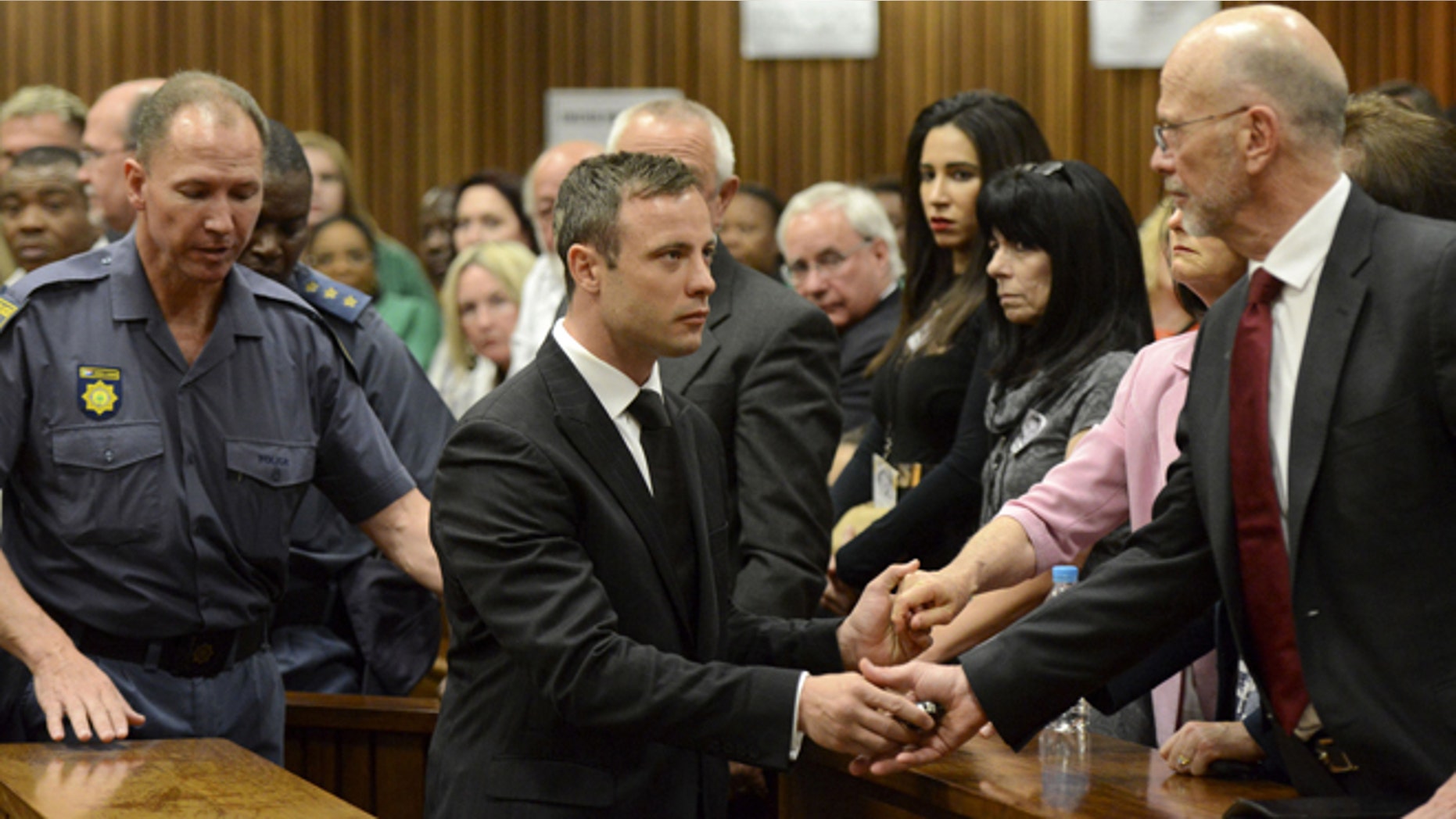 Oct. 21, 2014: Oscar Pistorius, center, greets his uncle Arnold Pistorius, right, and other family members as he is led down to the cells of the court in Pretoria, South Africa. Pistorius received a five-year prison sentence for culpable homicide by judge Thokozile Masipais for the killing of his girlfriend Reeva Steenkamp last year