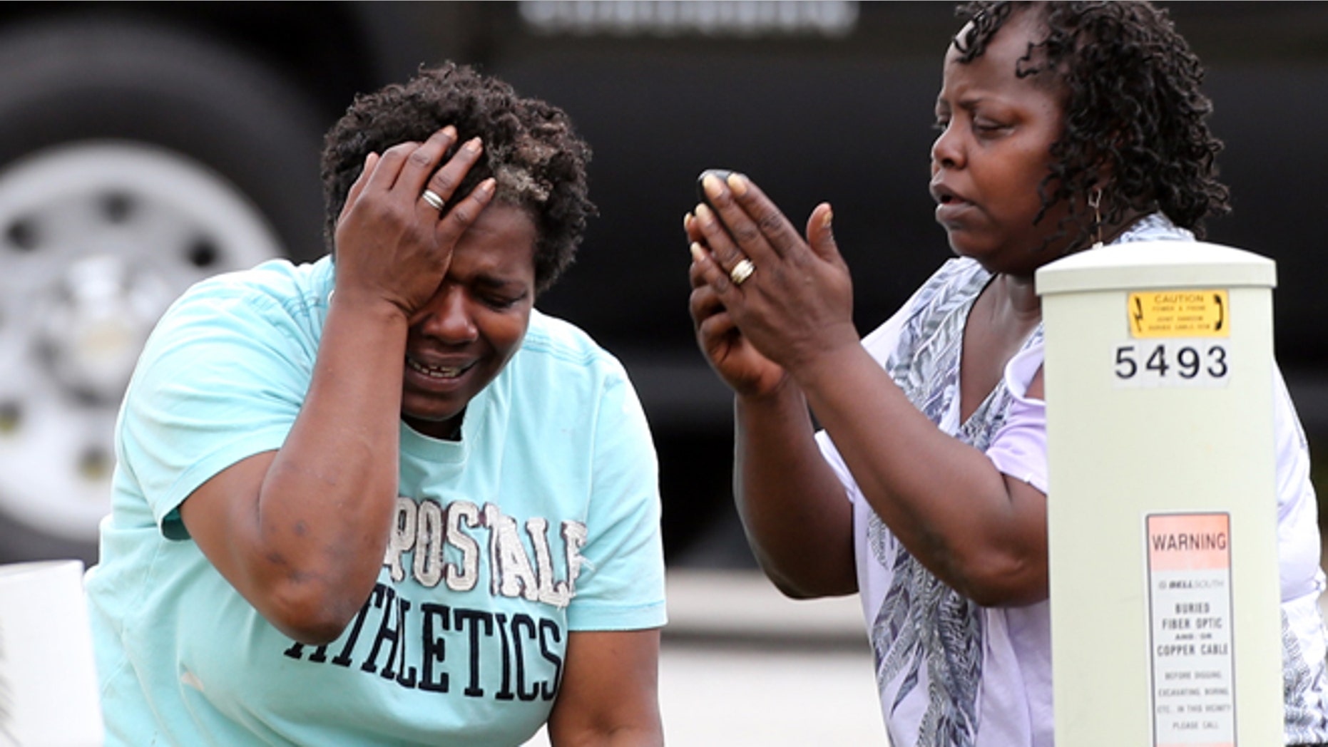 April 24: After finding out that a two-year-old had been killed by his South Fulton family's pit bull, a relative grieves and a family friend makes a call in an unincorporated area in south Fulton County near Union City, Ga.