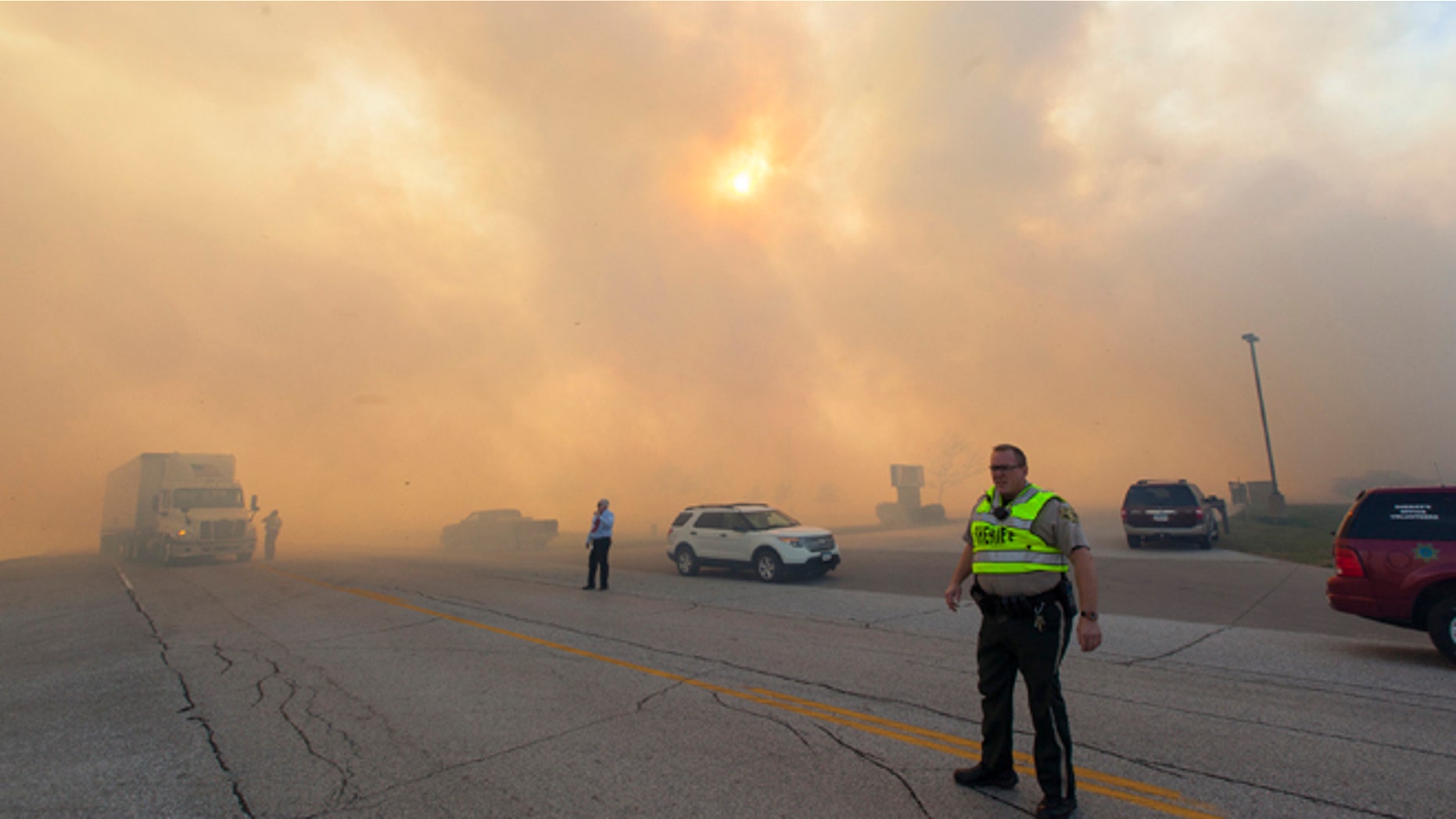 Oct. 12, 2015: Authorities direct traffic for vehicles passing through heavy smoke from a burning field in Eldridge, Iowa.