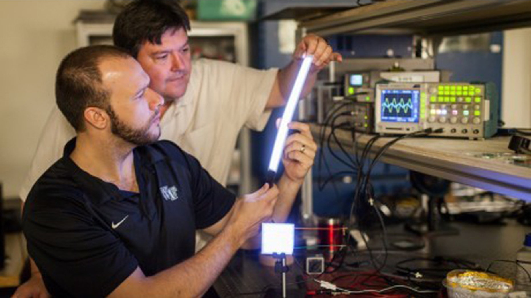 Researchers have made a new glowing plastic material that they've formed into lights of different shapes. Here, physicist David Carroll (front) and graduate student Greg Smith (behind) with a few of their creations.