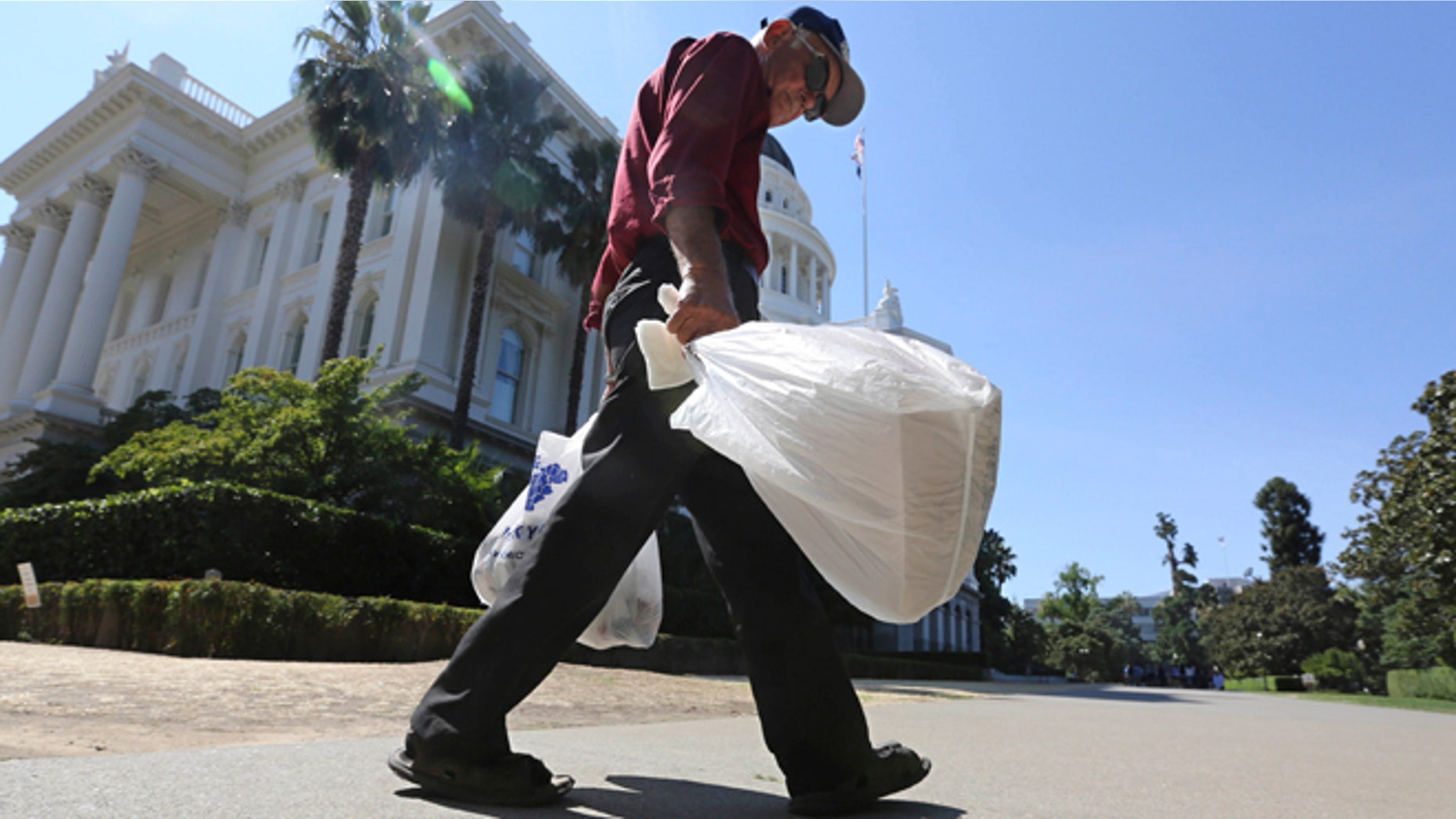 Aug. 12, 2014: File photo, a man carries plastic single-use bags past the State Capitol in Sacramento, Calif.