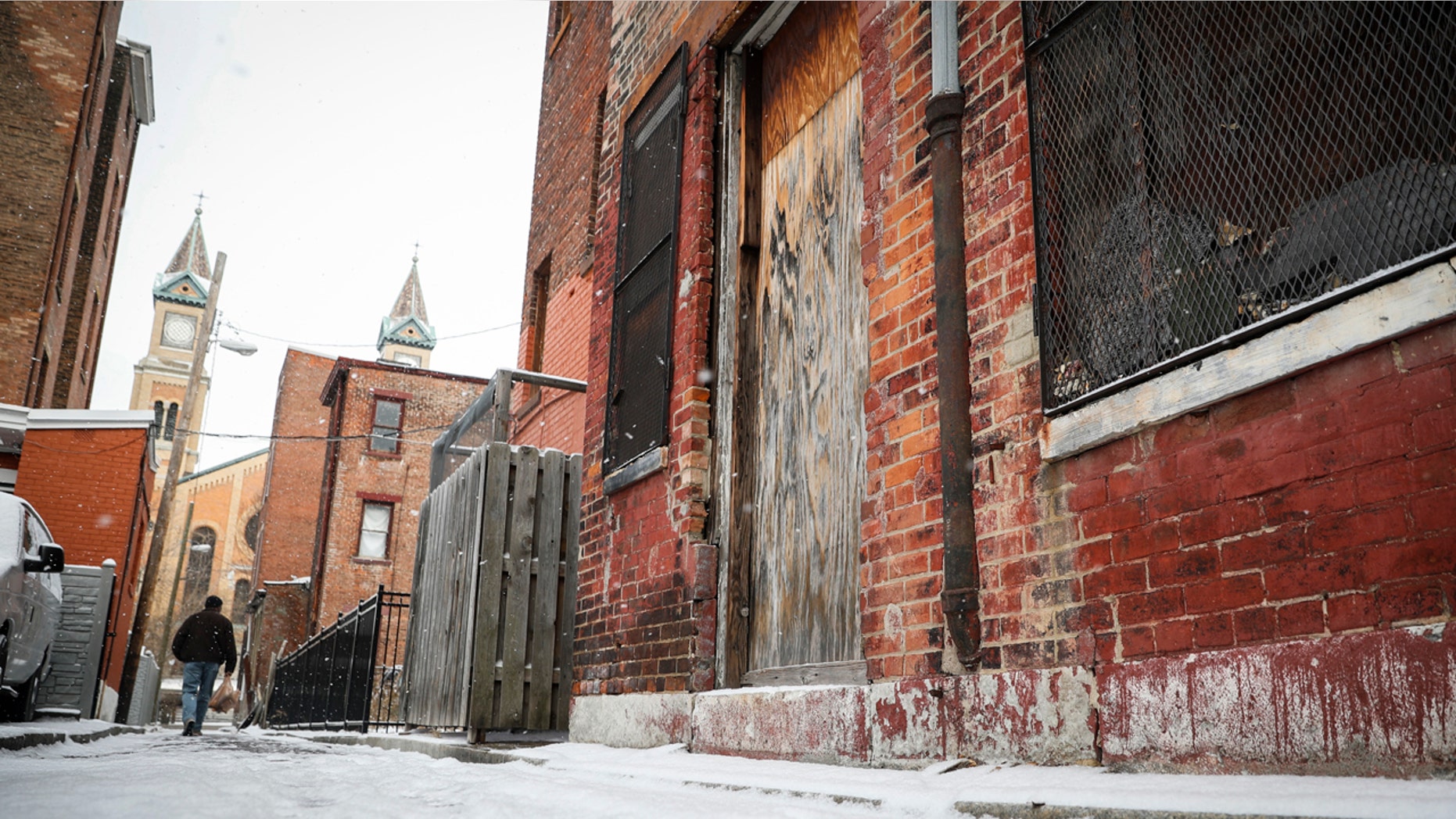 Pedestrians pass boarded up buildings in downtown Cincinnati, Thursday, Jan. 5, 2017.