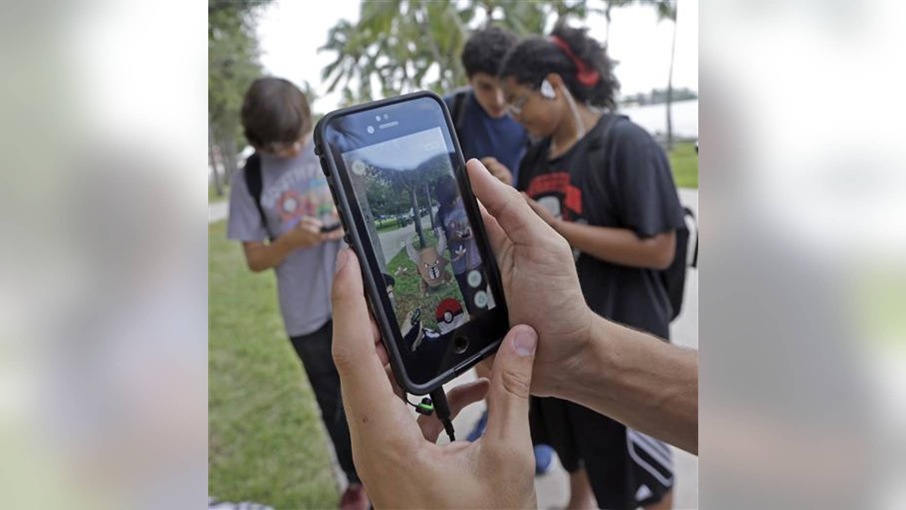 Pinsir, a Pokemon, is found by a group of Pokemon Go players at Bayfront Park in downtown Miami on July 12, 2016, as the "Pokemon Go" craze has sent legions of players hiking around cities and battling with "pocket monsters" on their smartphones. (AP Photo/Alan Diaz)