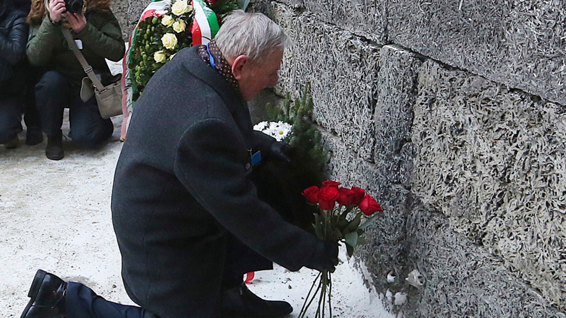 A holocaust survivor places flowers in commemoration of the people killed by the Nazis at the former Auschwitz Germany Nazi death camp in Oswiecim, Poland, Friday, Jan. 27, 2017, on the International Holocaust Remembrance Day that marks the liberation of the Auschwitz Nazi death camp on Jan. 27, 1945.(AP Photo/Czarek Sokolowski)