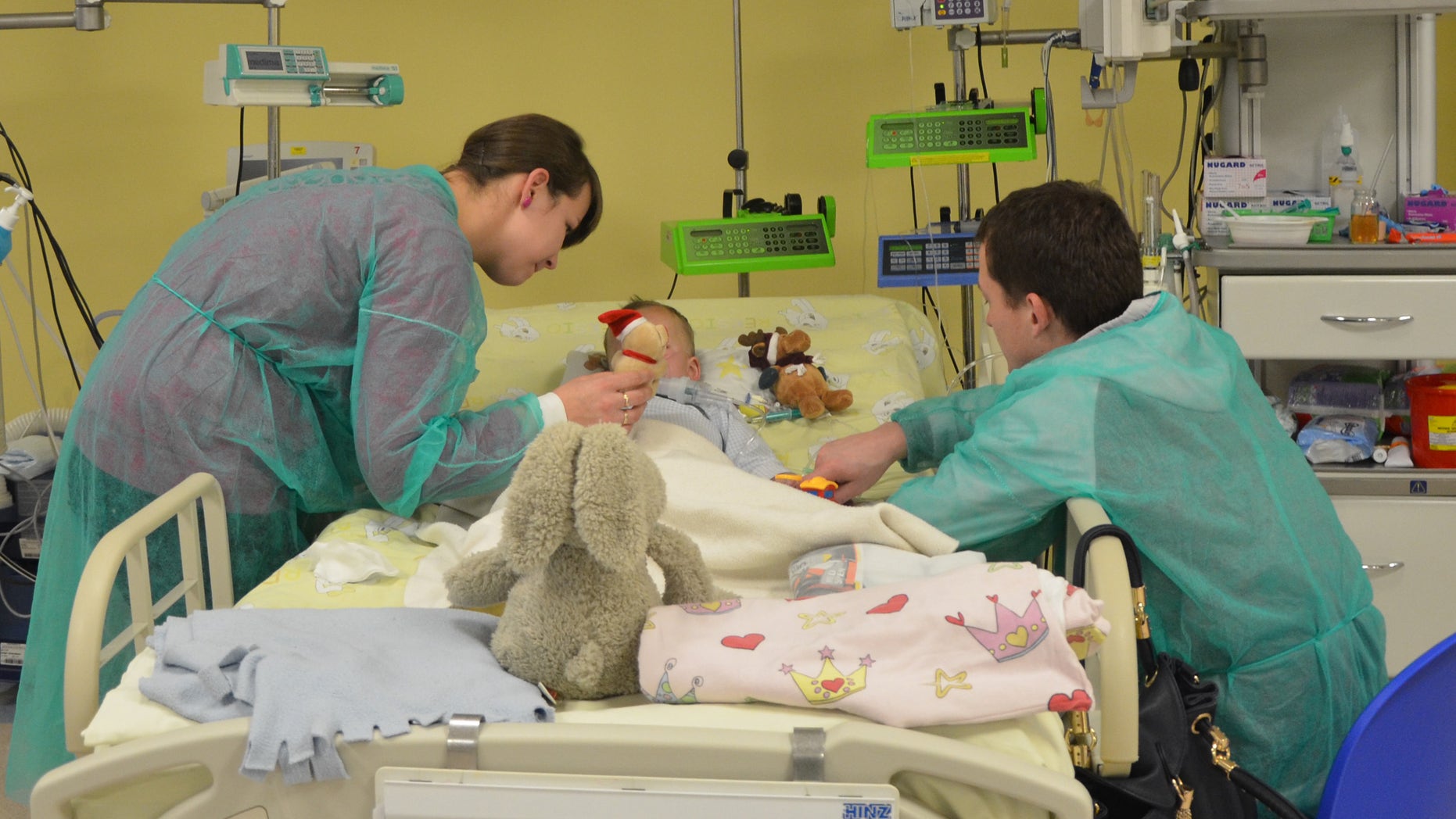 In this photo taken by Magdalena Oberc, the spokeswoman of the childrens hospital in Krakow, Poland, on Thursday, Dec. 4, 2014, a 2-year-and-4-months-old Adam is seen with his mother Paulina, his father Mateusz and a teddy bear, just a few days after he was brought to the hospital with his temperature at only 12.7 C (55 F) and his heart beating once every few dozen seconds after being found outdoors in sub-freezing temperature on Sunday morning with almost no clothes on. Dr. Janusz Skalski, a heart surgeon at the hospital, said its a miracle that the boy is showing no negative signs from the hours that he spent in such low temperature. (AP Photo/Magdalena Oberc, Krakow Childrens Hospital spokeswoman)