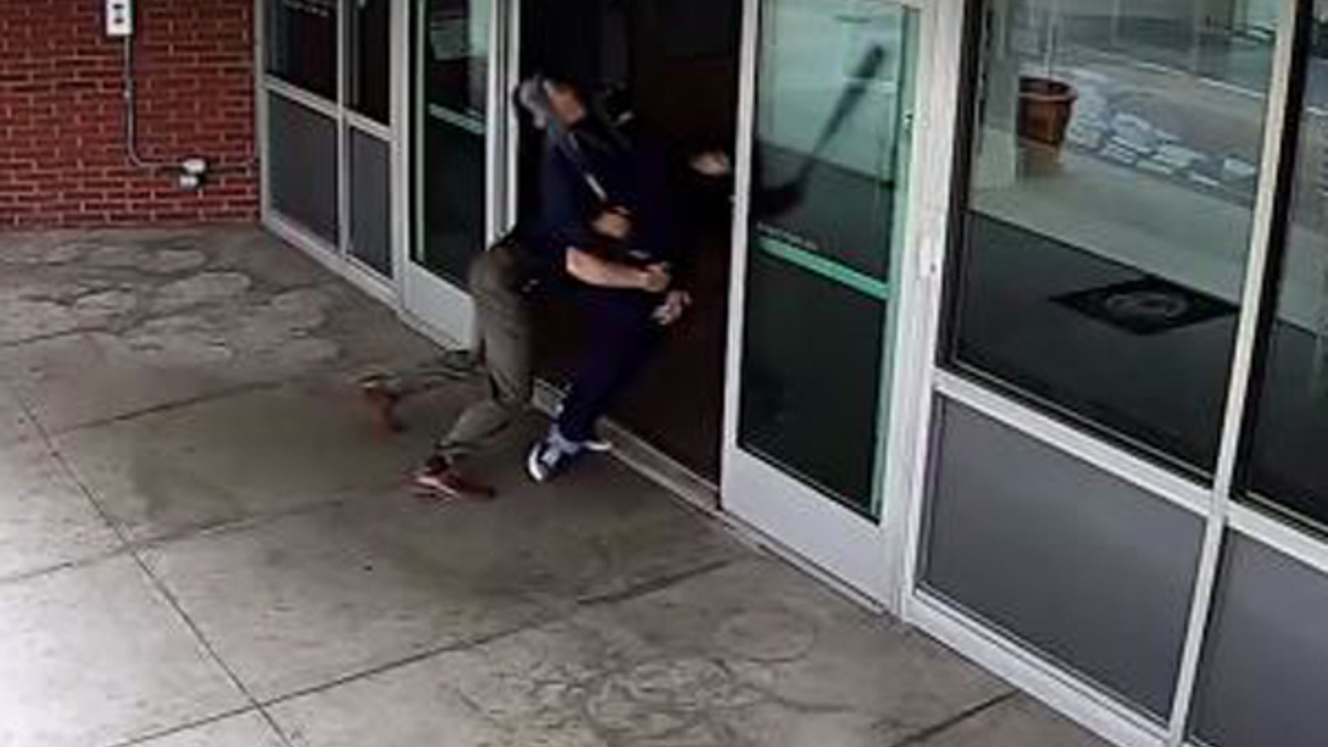 A man is tackled after swinging a bat at the window of the poilce department in West Covina, Calif.
