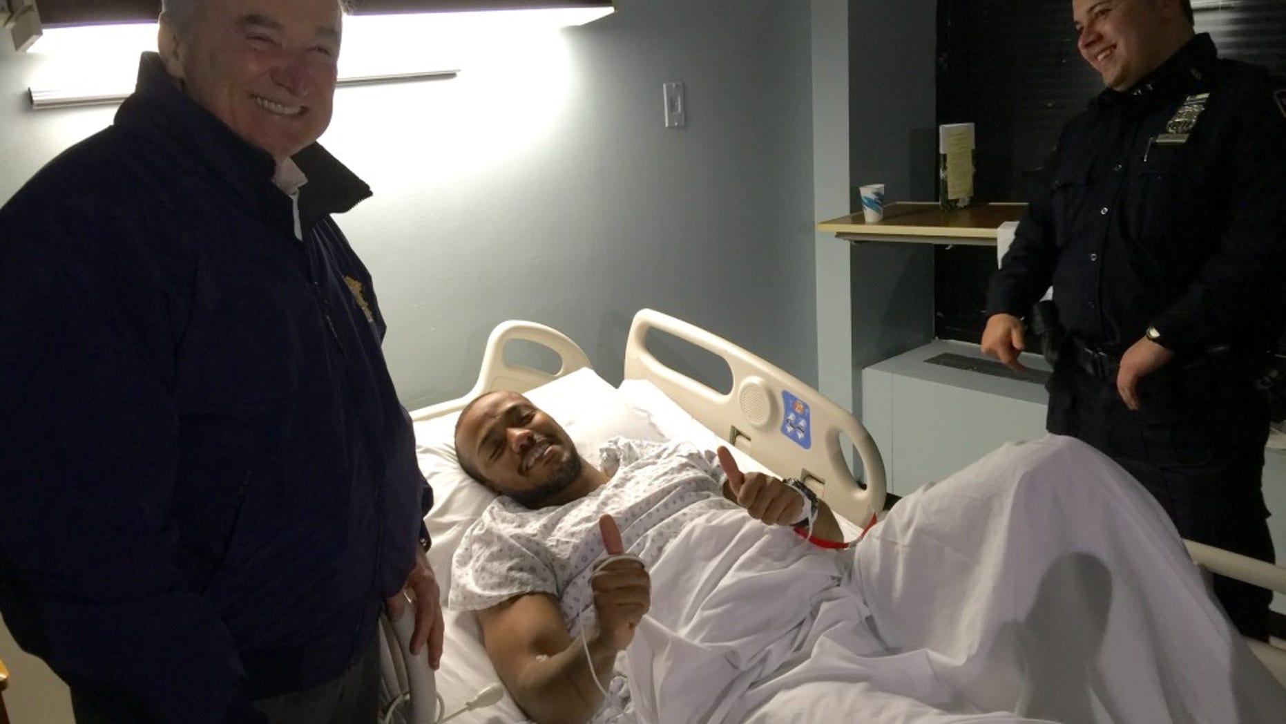 Police Commissioner Bill Bratton, left, stands next to injured cop Sherrod Stuart as an unidentified officer looks on.