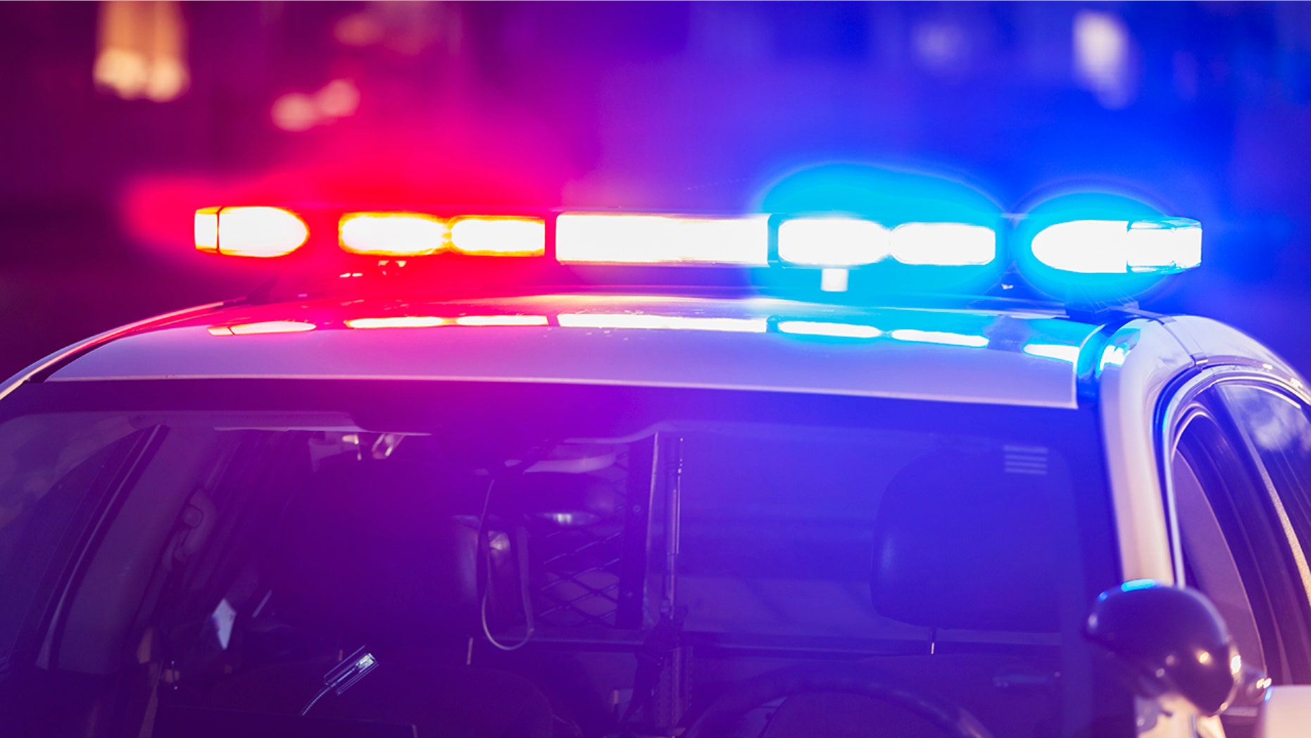 The roof of a police patrol car at night, with the blue and red lights flashing.