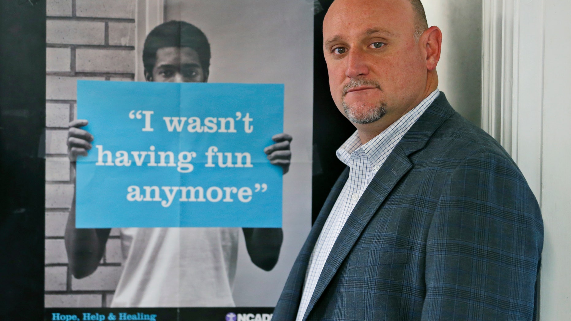 In this Monday, Dec. 5, 2016, photo, David Rook, operations manager for the McShin Foundation, poses next to a poster in the foundation's offices in Richmond, Va.
