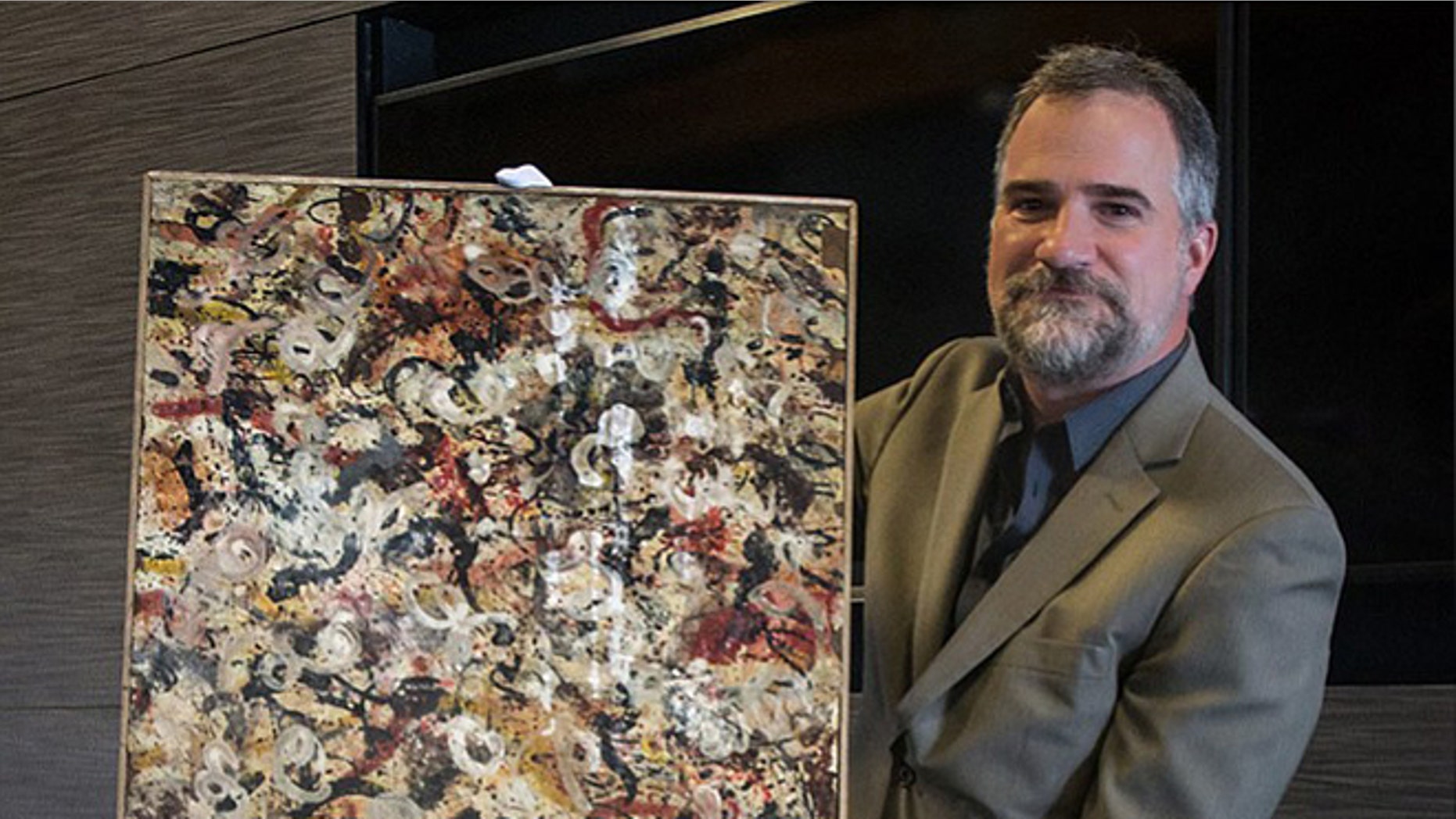 Auctioneer Josh Levine holds a painting that he believes is an original Jackson Pollock and that will go up for auction June 20.