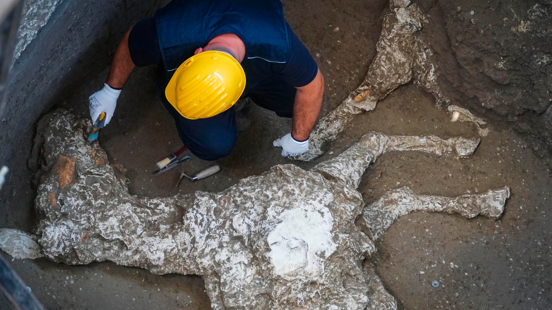 In this picture taken Thursday, May 10, 2018, an archaeologist works near the remains of a horse found in the stable of a Pompeii villa, near Naples, Southern Italy. (Cesare Abbate/ANSA via AP)