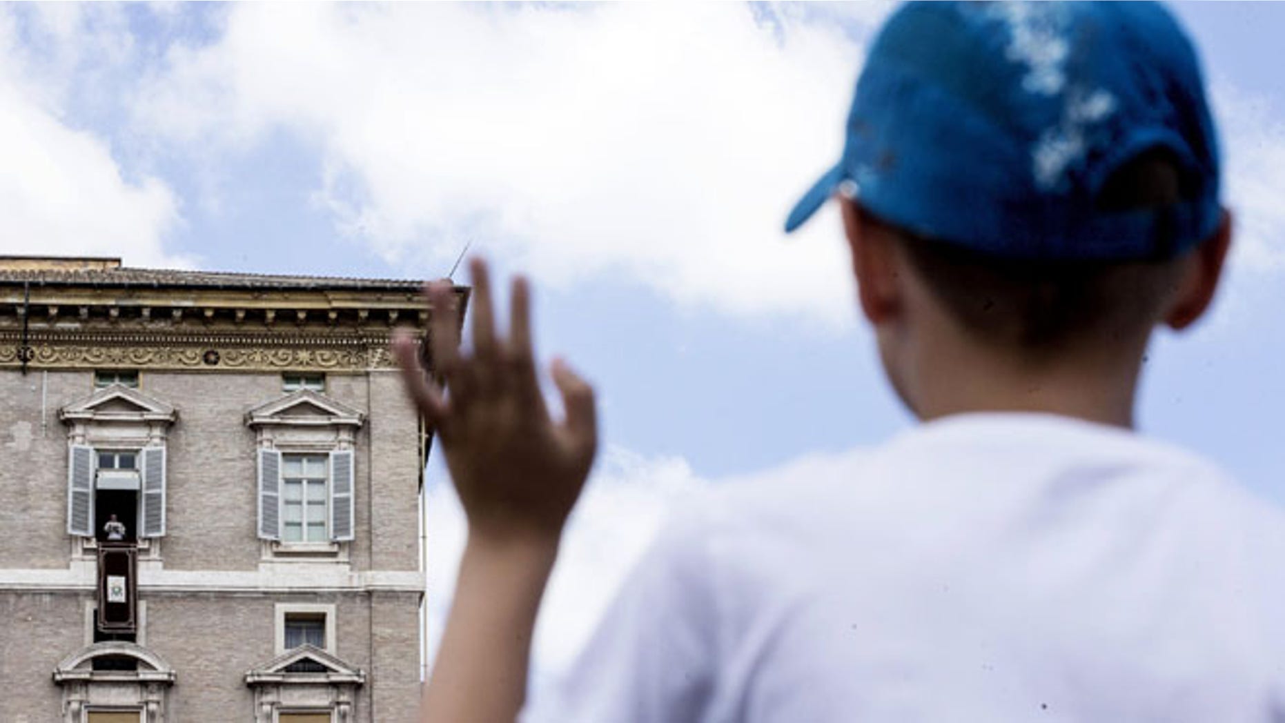 A young boy waves as Pope Francis delivers his message from his studio window overlooking St. Peter's Square during the Sunday Angelus prayer, at the Vatican, Sunday, Aug. 14, 2016. (Angelo Carconi/ANSA via AP)