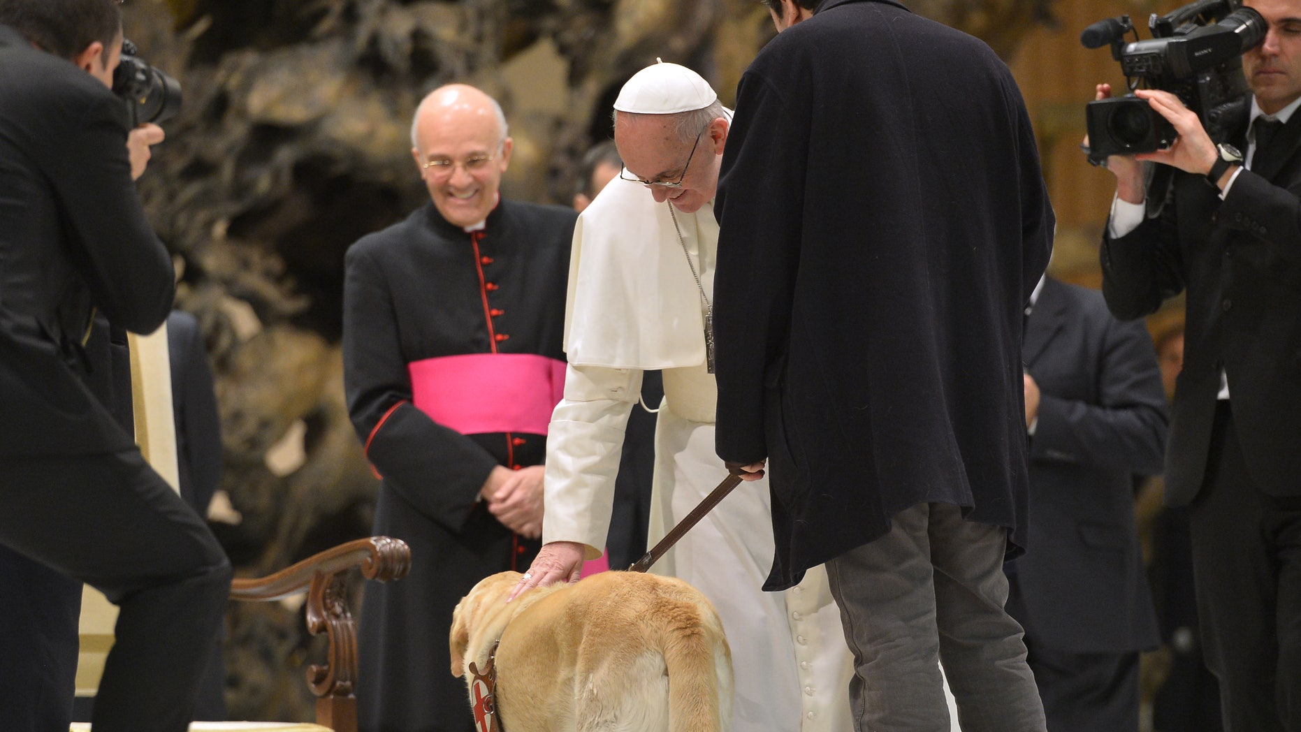 Pope Francis caresses a guide dog during a private audience to members of the media on March 16, 2013 at the Paul VI hall at the Vatican. Pope Francis called for "a poor Church for the poor", saying he chose his papal name because St Francis of Assisi was "a man of poverty and a man of peace". AFP PHOTO / ALBERTO PIZZOLI (Photo credit should read ALBERTO PIZZOLI/AFP/Getty Images)