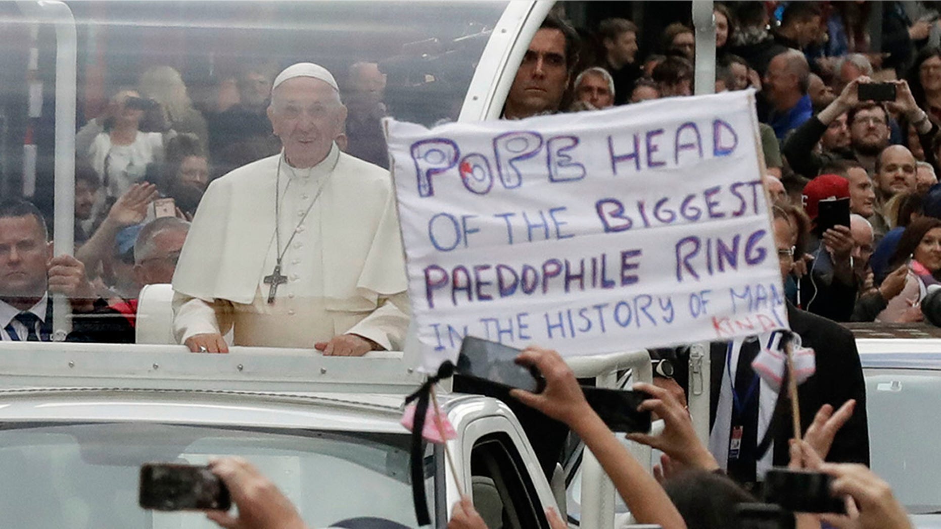 Pope Francis passes a protester's banner as he leaves St. Mary's Pro-Cathedral in Dublin Saturday.