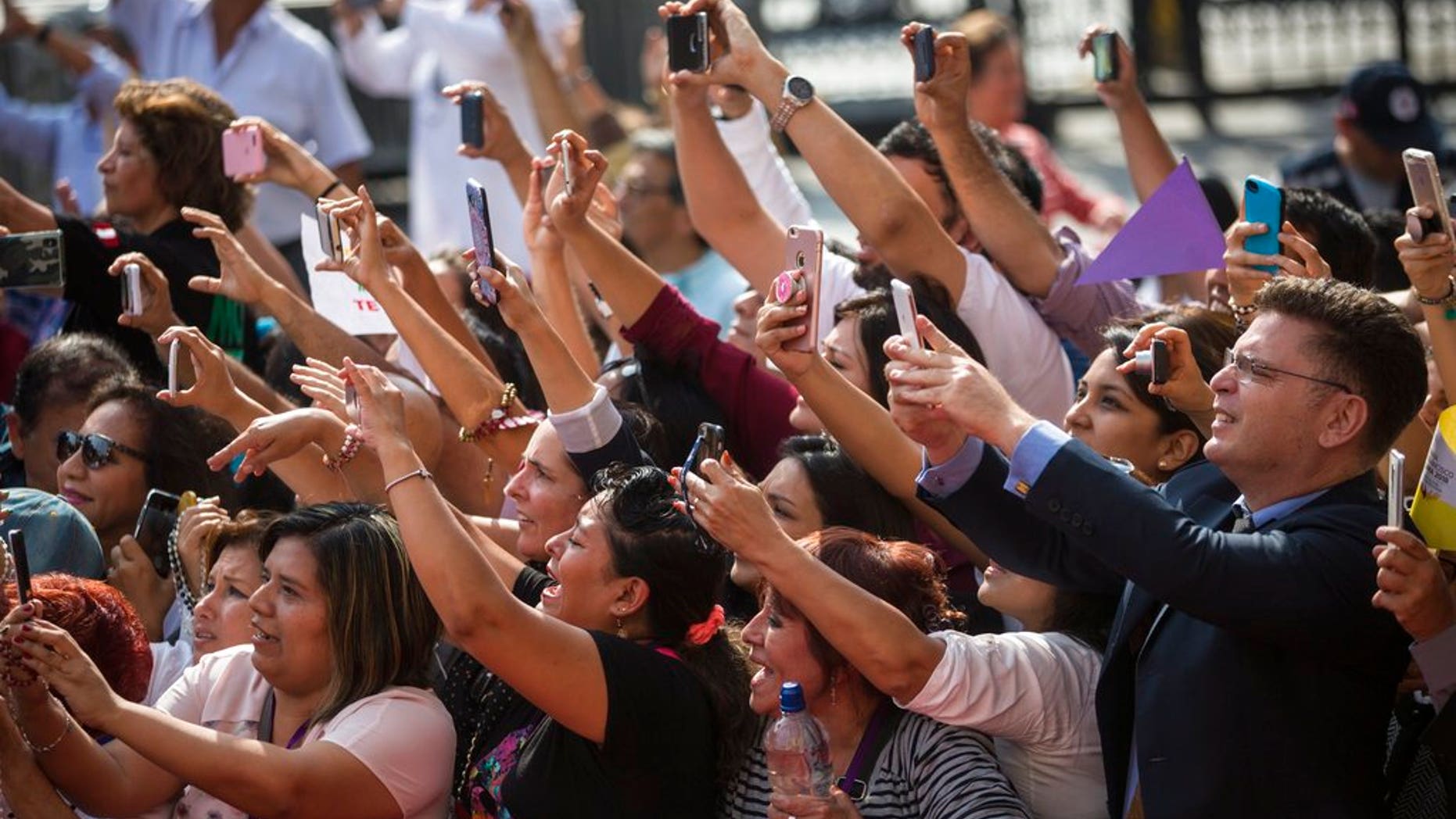 A crowd of people aiming phones at Pope Francis as he arrives for a mid-morning prayer in Lima, Peru, on Sunday.